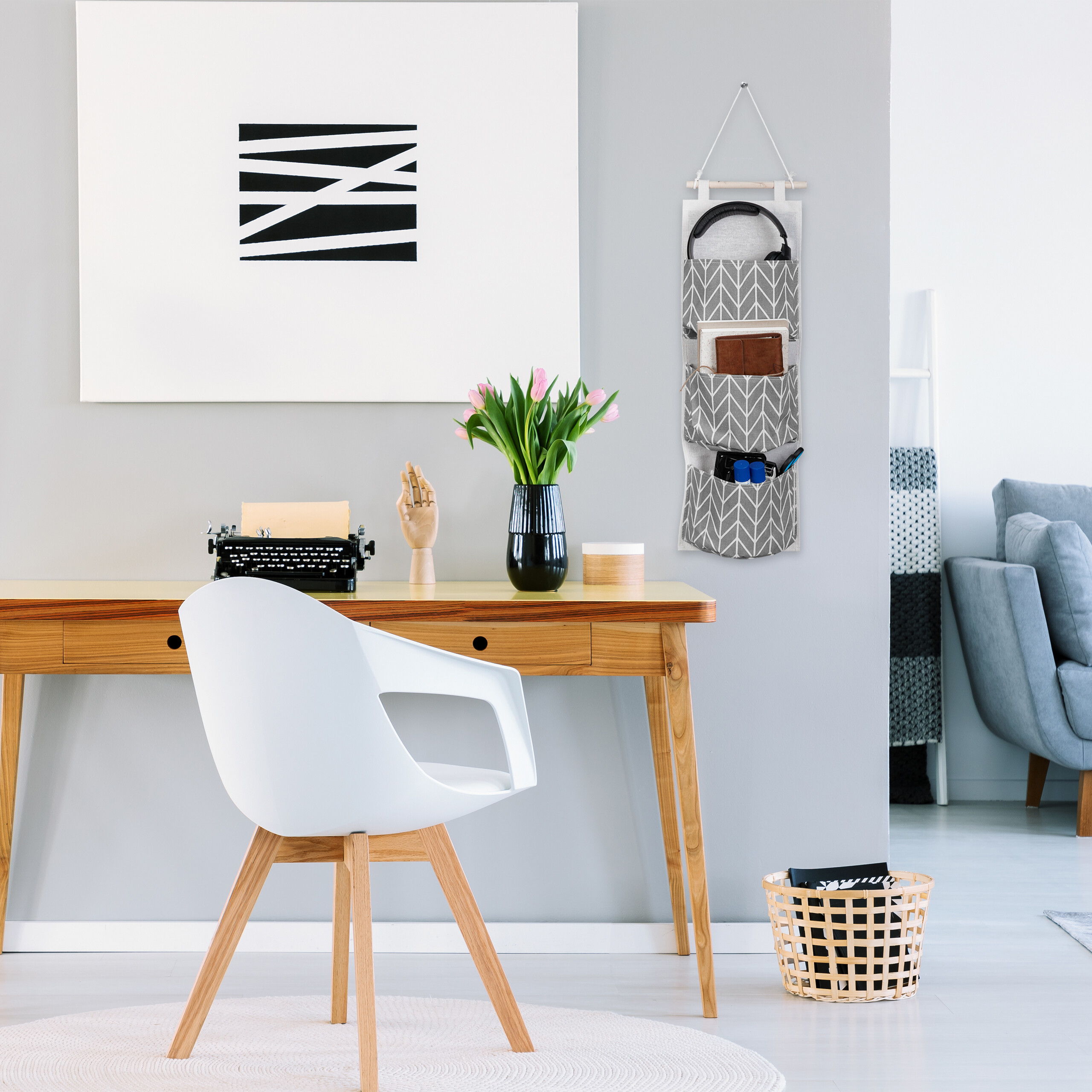 Ein modernes Homeoffice mit Holztisch, weißem Stuhl, Schreibmaschine, rosa Tulpen und Wandkunst.