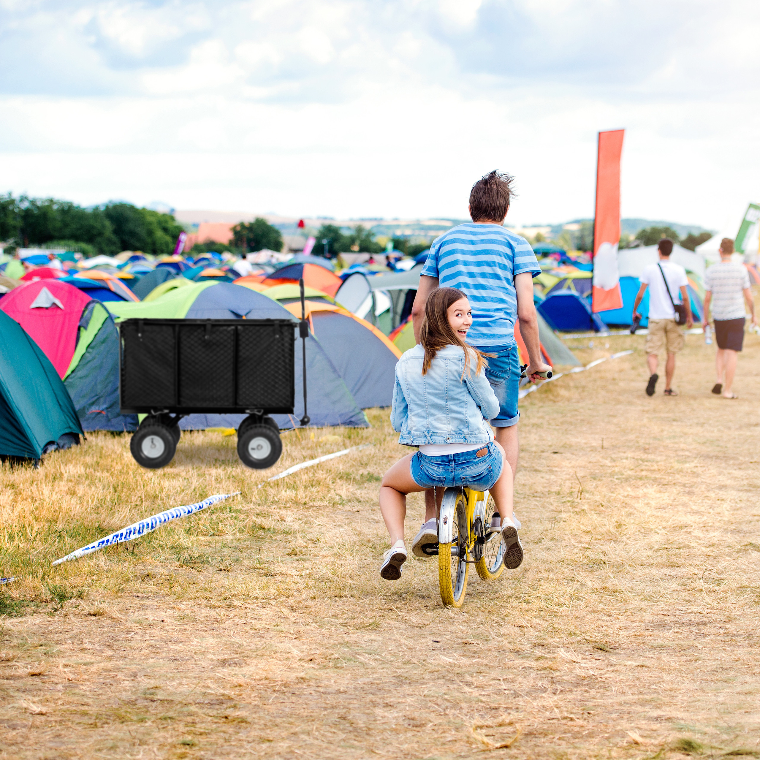 Ein Paar fährt Fahrrad bei einem Festival, umgeben von bunten Zelten im Hintergrund.