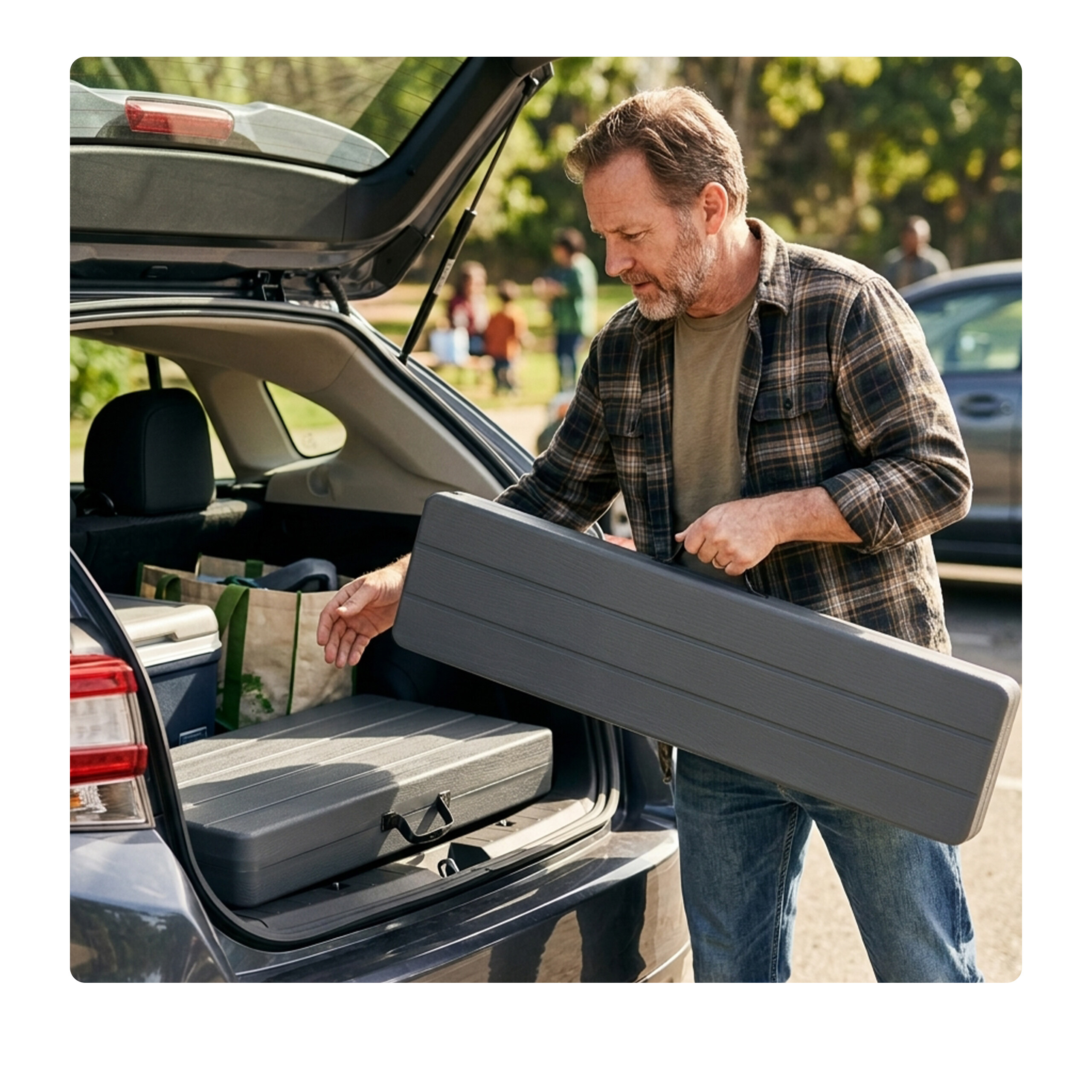 Ein Mann nimmt eine graue Klappbox aus dem Kofferraum eines Autos.