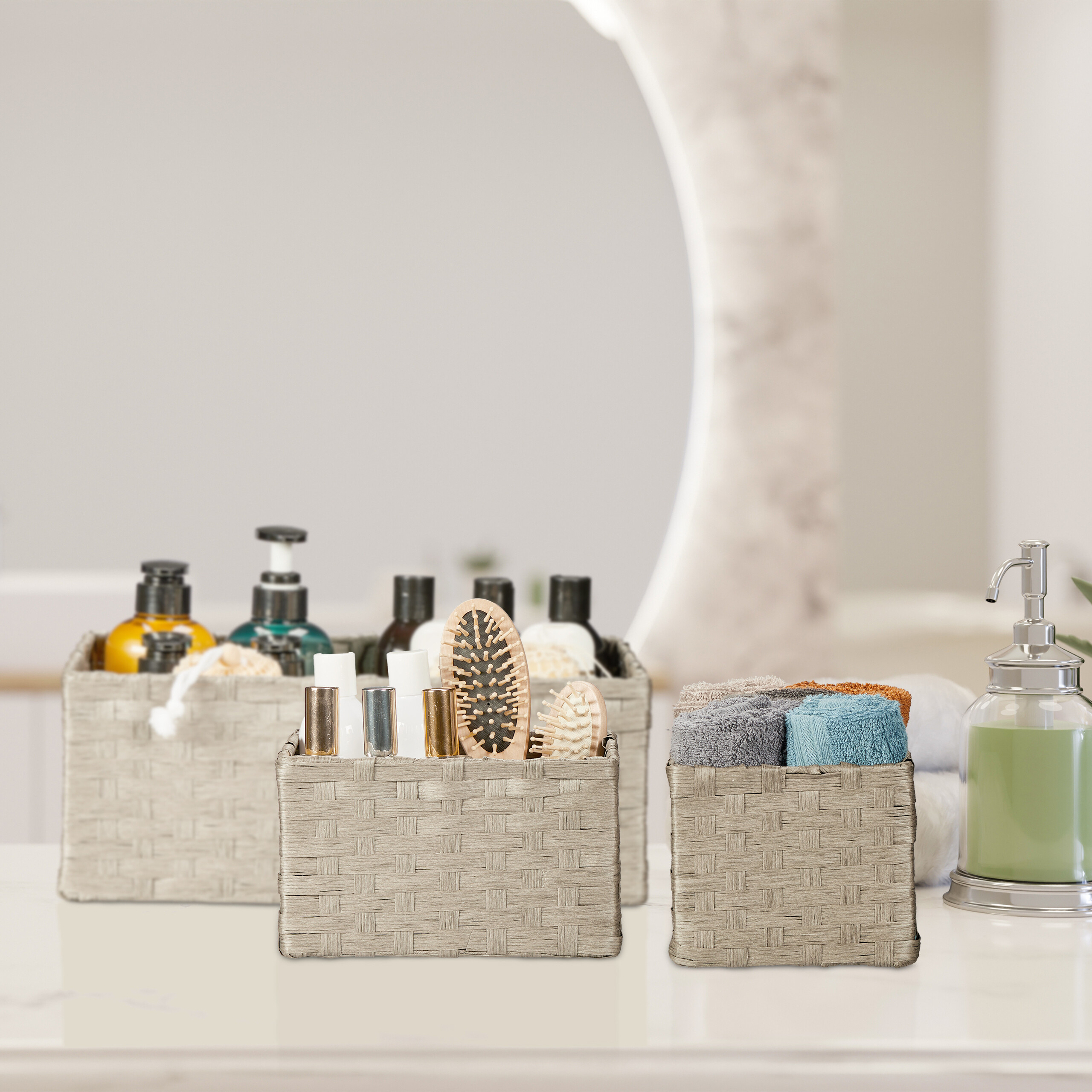 Badezimmer-Arbeitsplatte mit gewebten Körben voll Kosmetik, Bürsten, gefalteten Handtüchern und Seifenspender.