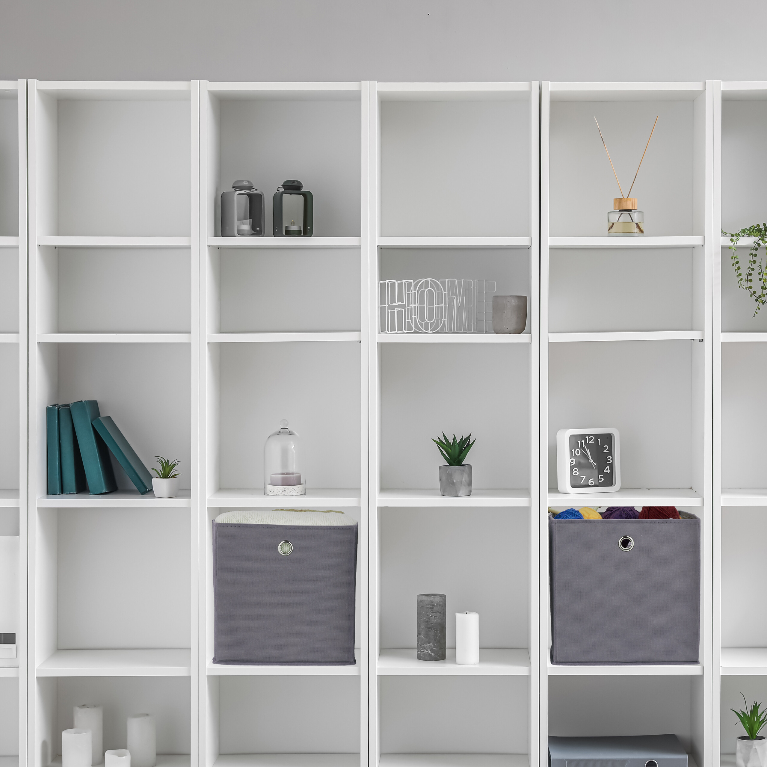 Ein großes weißes Regal mit Büchern, Pflanzen, Deko-Objekten und Aufbewahrungsboxen.