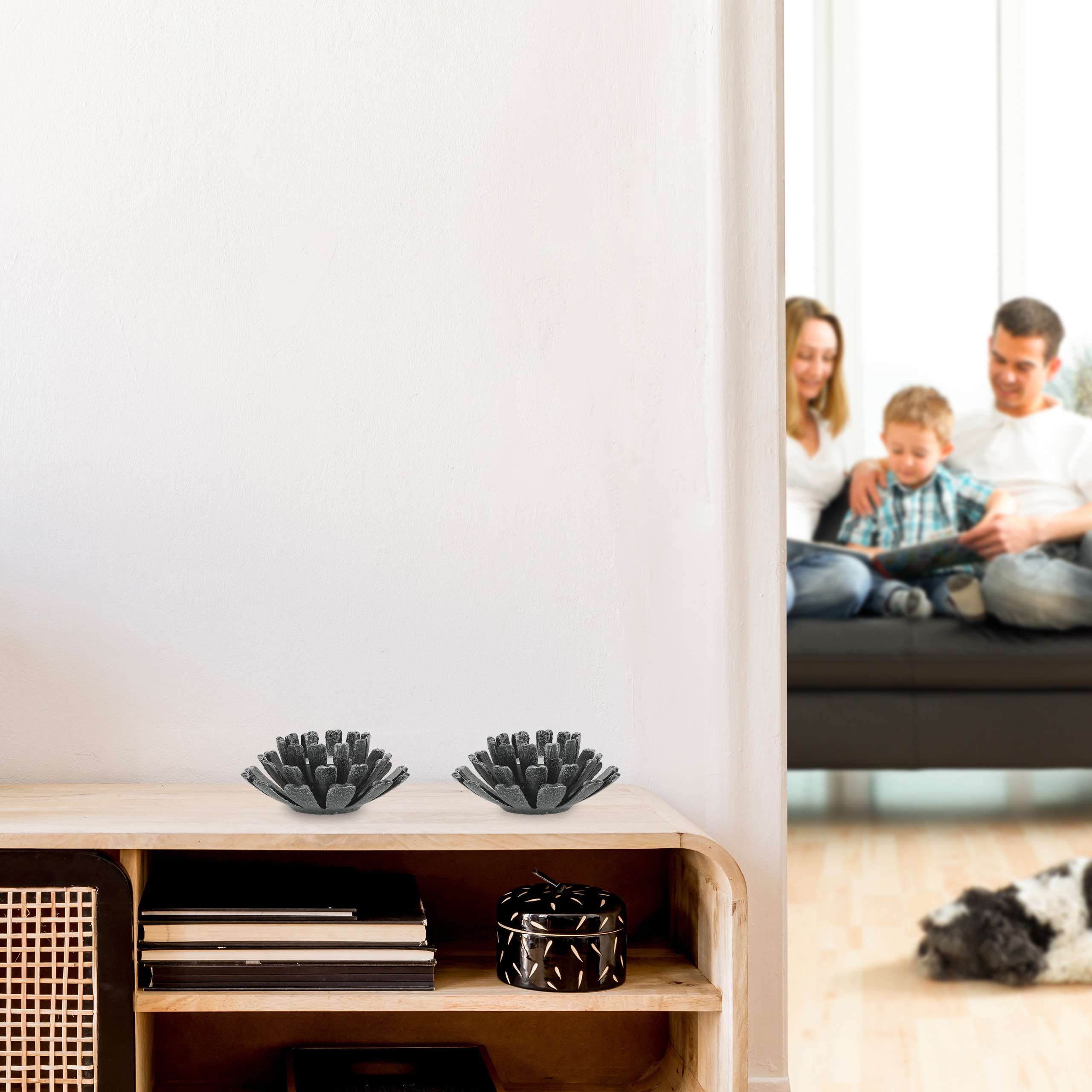 Ein Holzschrank mit dunklen Zierschalen oben; eine verschwommene Familie im Hintergrund.