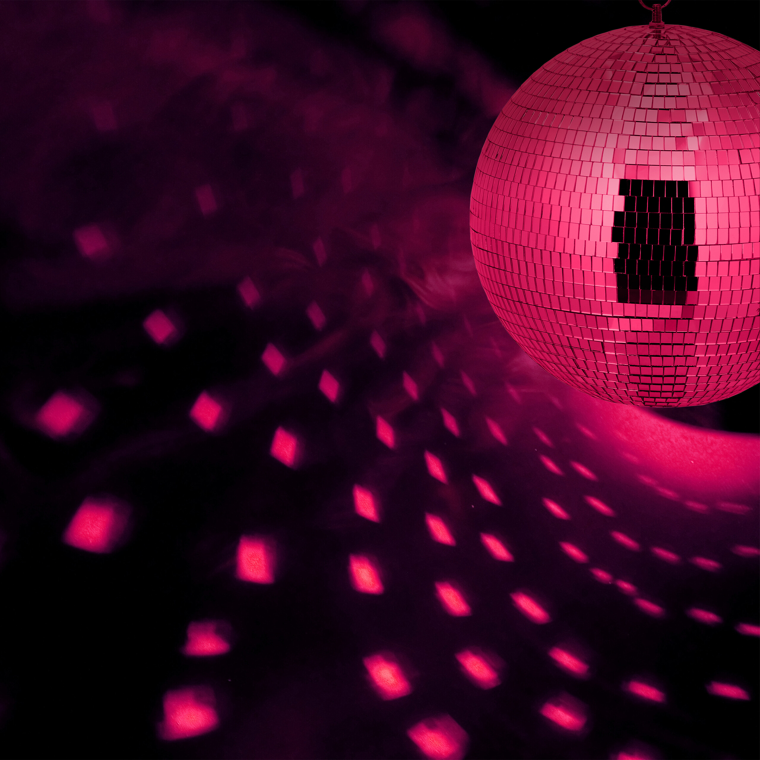 Eine pinke Diskokugel strahlt helles, pinkes Licht und wirft tanzende Lichtreflexe an eine dunkle Wand.