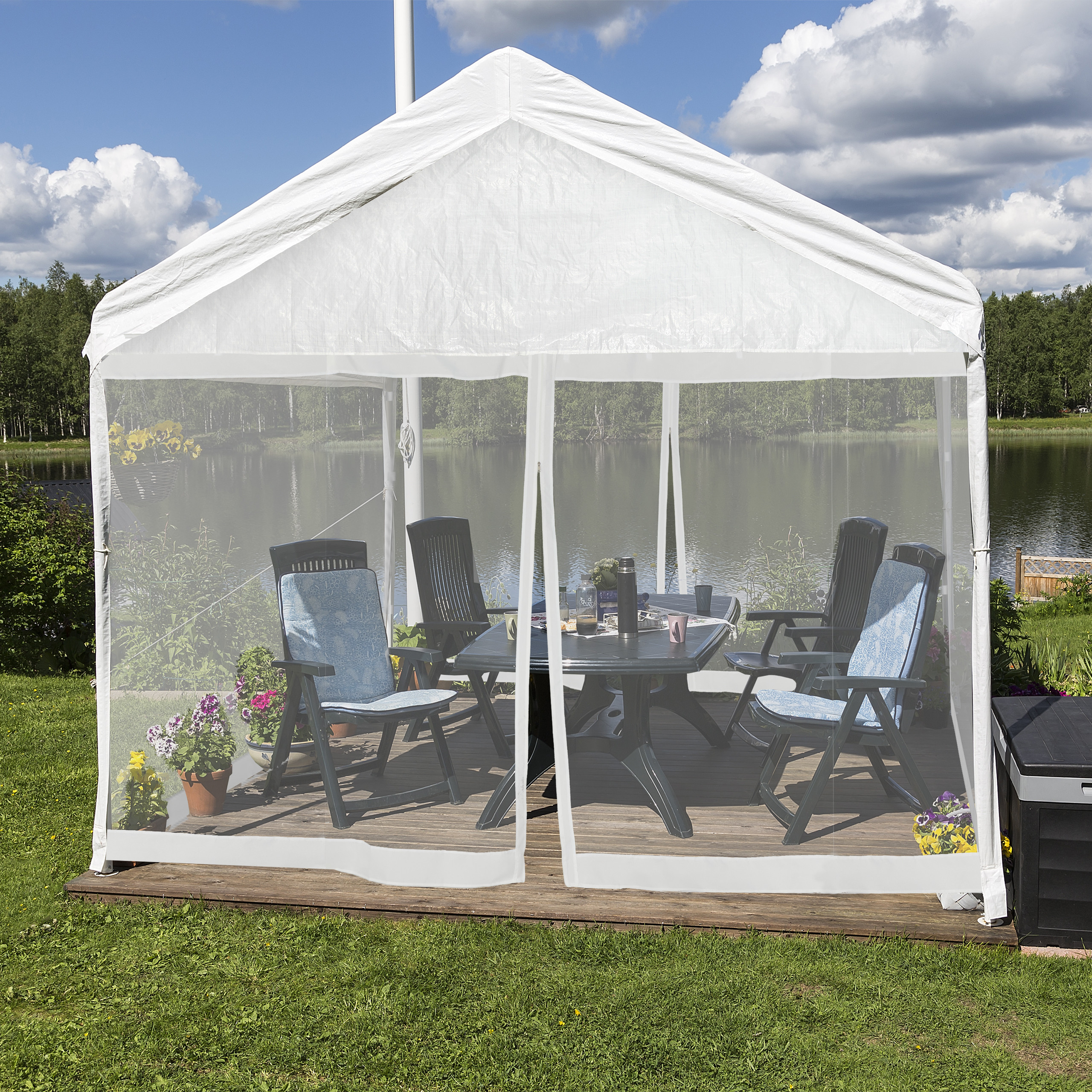 Ein weißer Pavillon mit Netzwänden umschließt Tisch und Stühle auf einer Holzterrasse am See.
