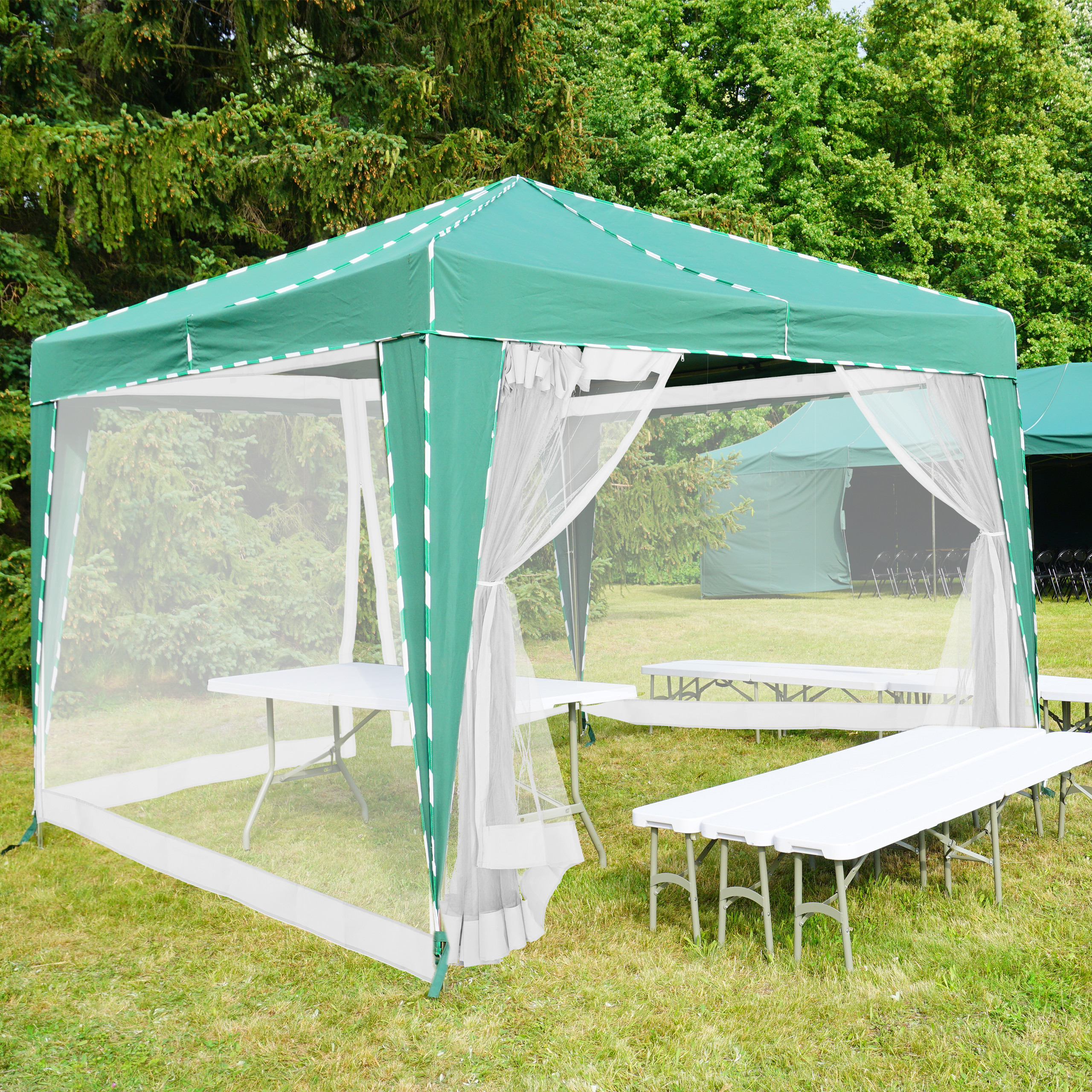 Ein grünes Faltpavillon mit weißen Netzwänden, Tischen und Bänken auf einer Rasenfläche mit Bäumen im Hintergrund.