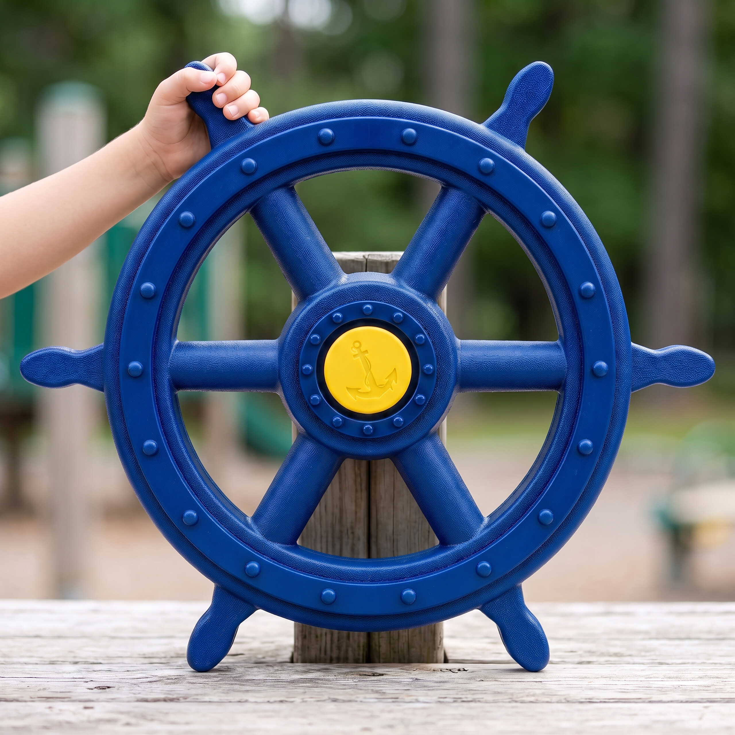 Ein Kind dreht das blaue Steuerrad mit gelbem Anker auf einem Spielplatz.