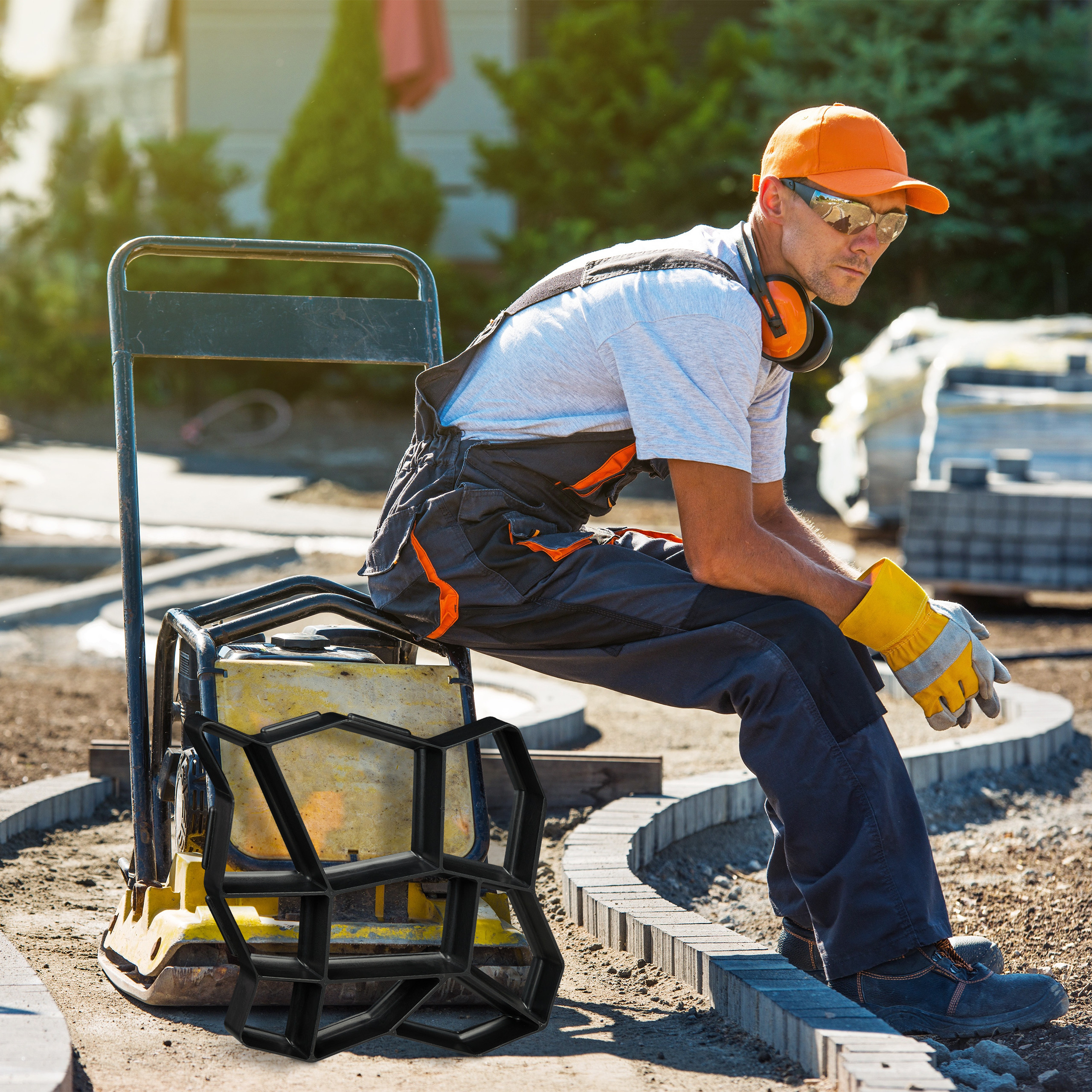 Ein Arbeiter in Schutzkleidung sitzt auf Baumaschinen im Freien.