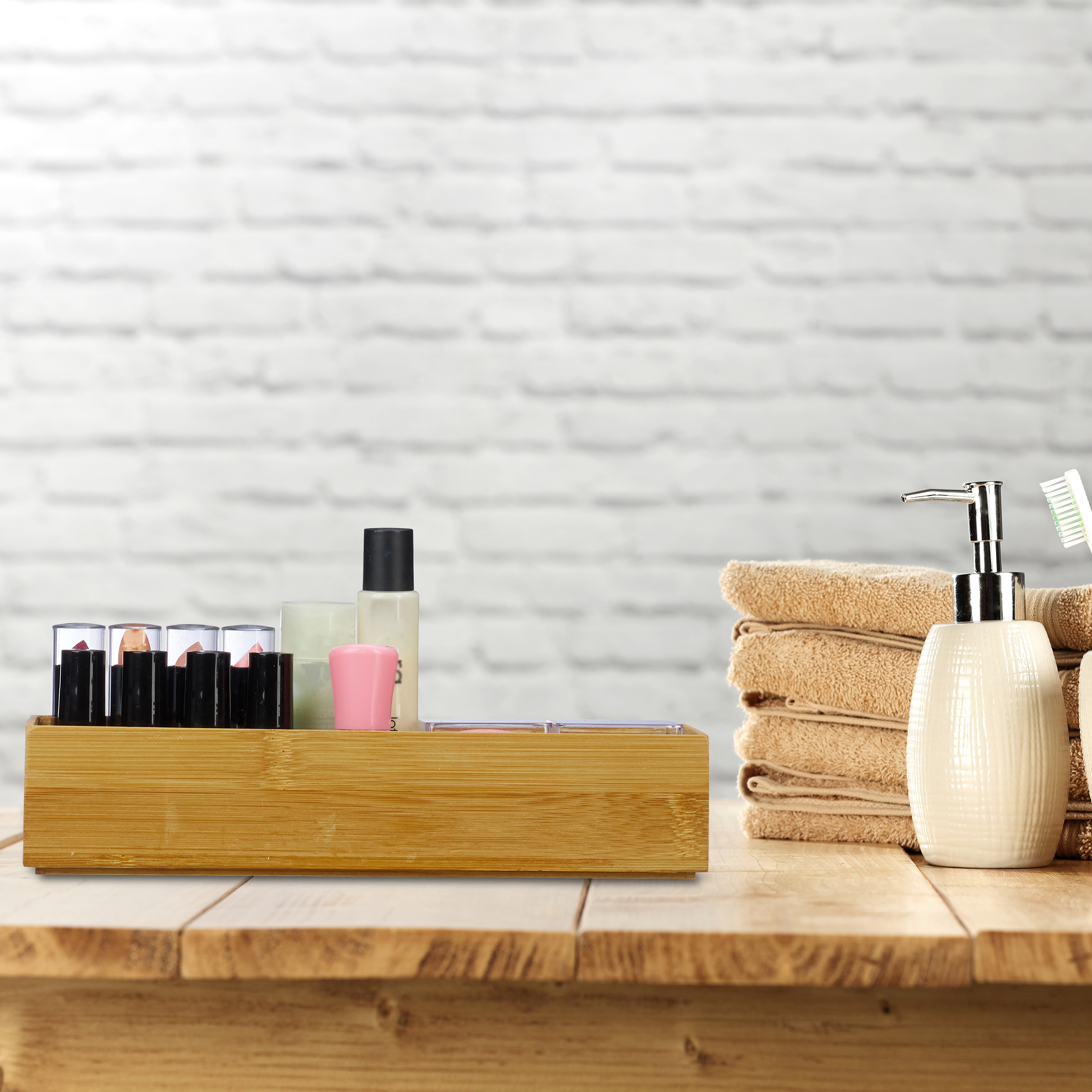 Badezimmer-Organizer mit Lippenstiften, Kosmetik, Handtüchern und Seifenspender auf Holz.