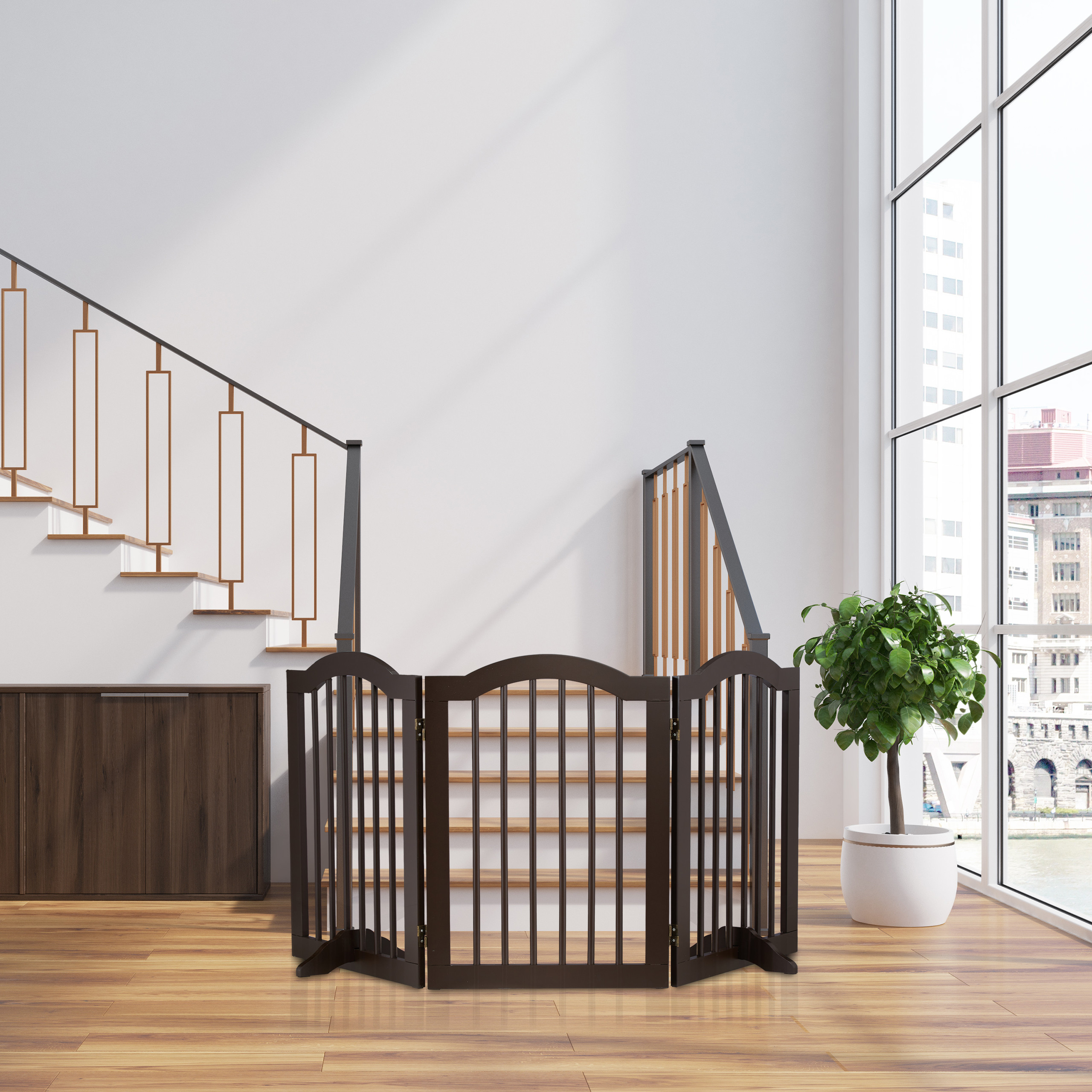 Ein braunes Holzgitter vor Treppen in einem hellen Raum mit großer Fensterfront und Pflanze.