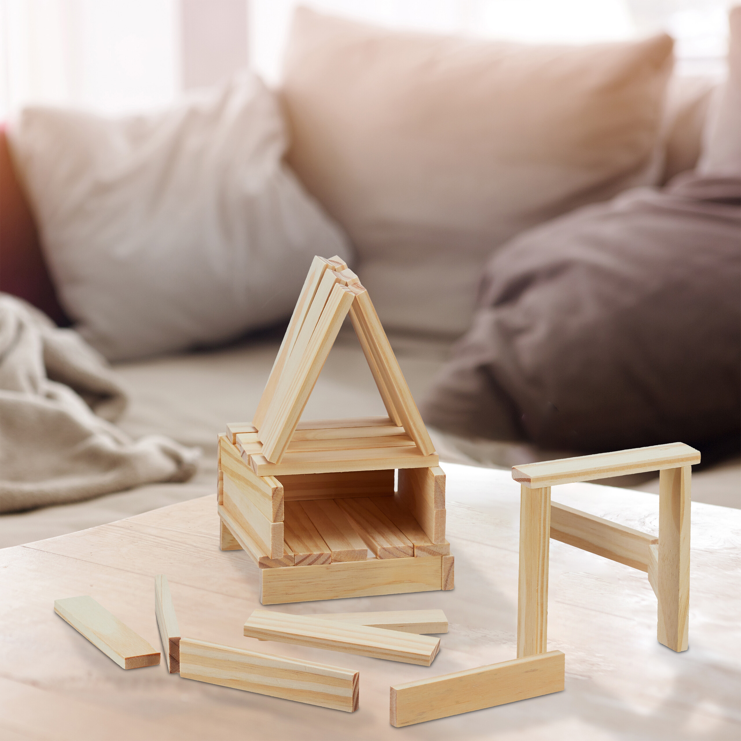 Holzspielzeug auf einem Tisch vor einer Couch mit Kissen.