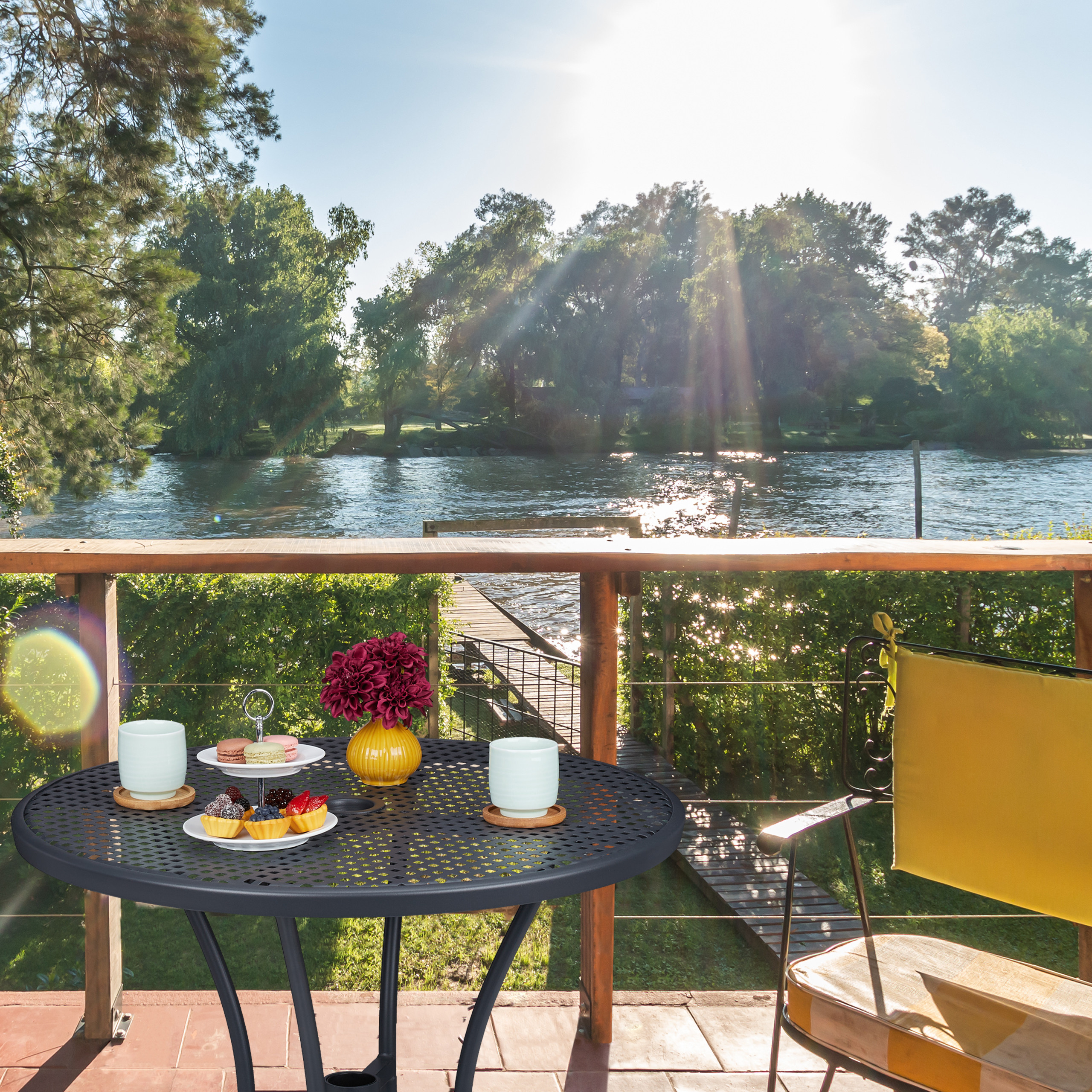 Ein Tisch mit Desserts und Kaffee auf einer Terrasse mit Blick auf einen Fluss und Bäume.