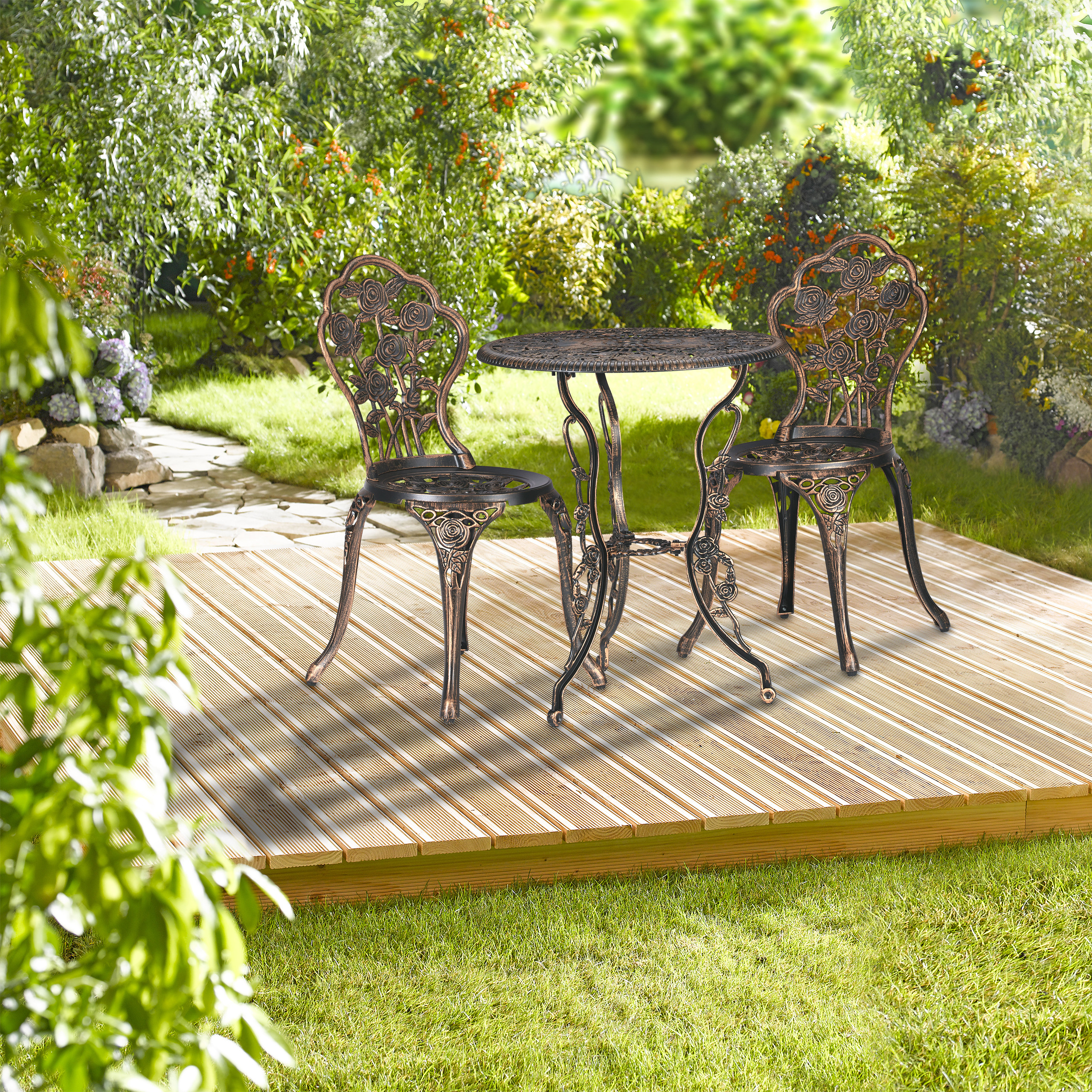 Ein antikes Bistromöbel-Set mit einem Tisch und zwei Stühlen steht auf einer Holzterrasse im üppigen Garten.