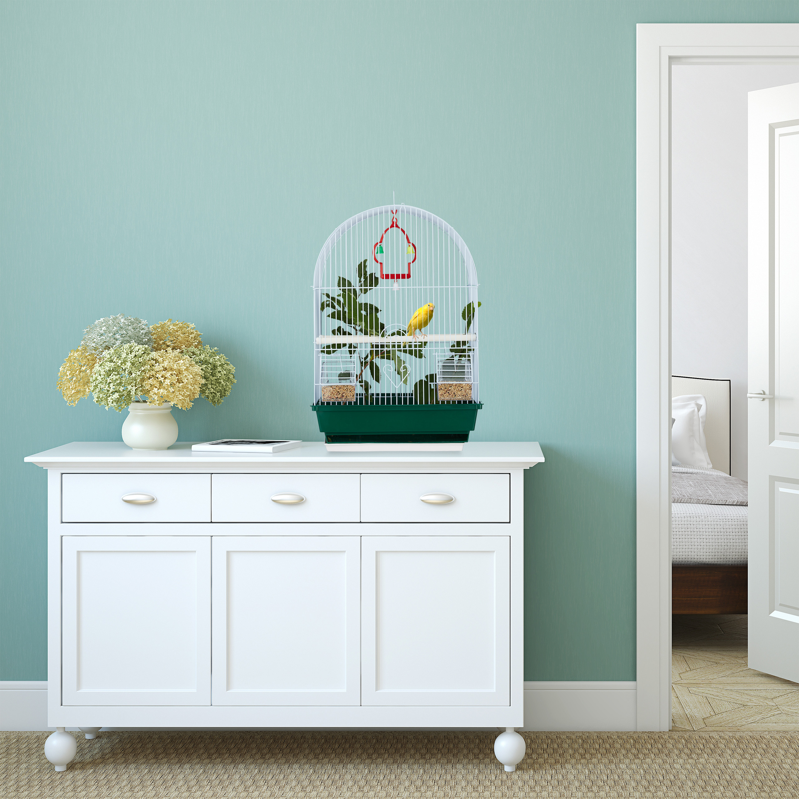 Ein weißer Schrank mit Blumen und einem Vogelkäfig davor, gegen eine mintgrüne Wand.