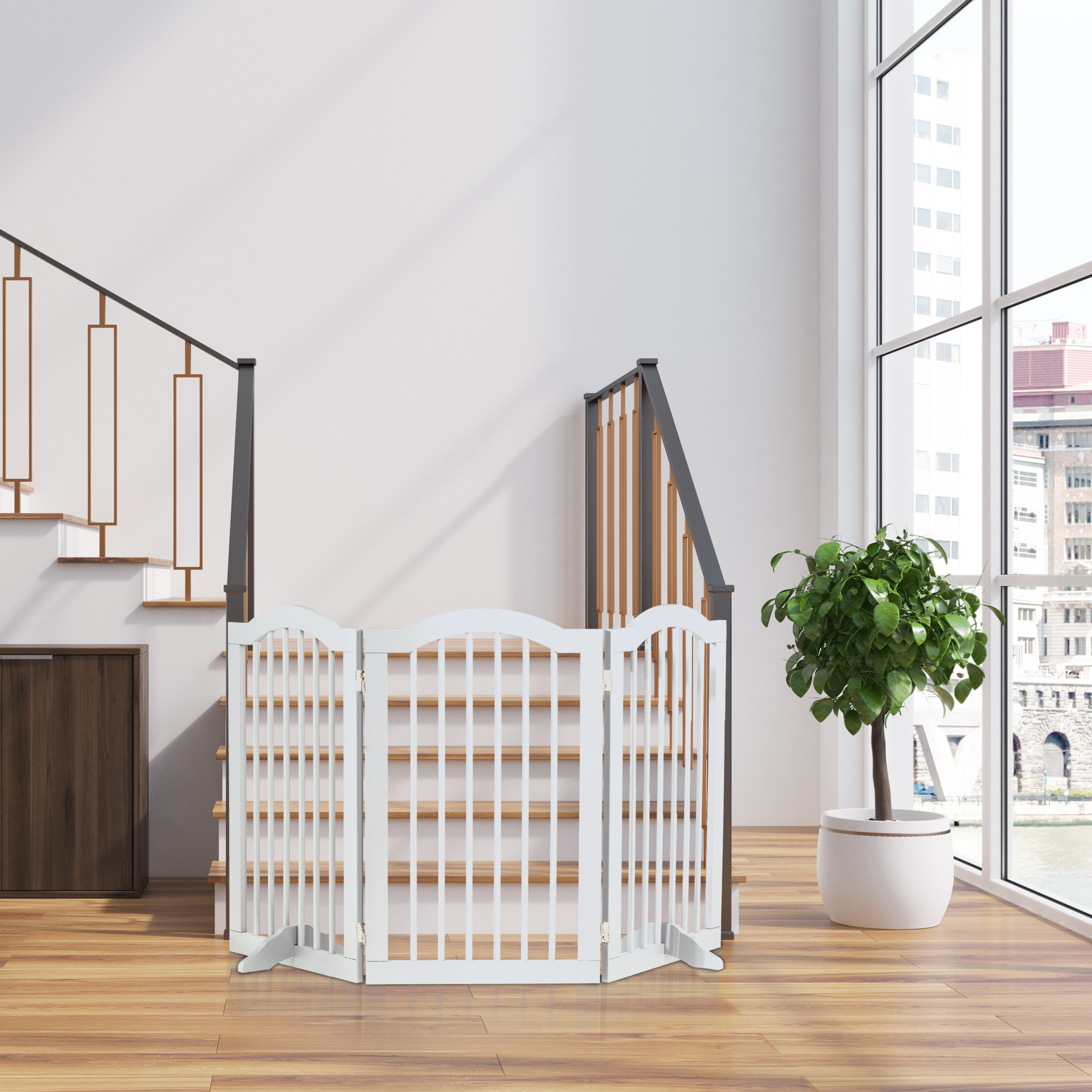 Ein weißes Holzschutzgitter steht vor Treppen in einem hellen Raum mit großer Fensterfront und Pflanze.