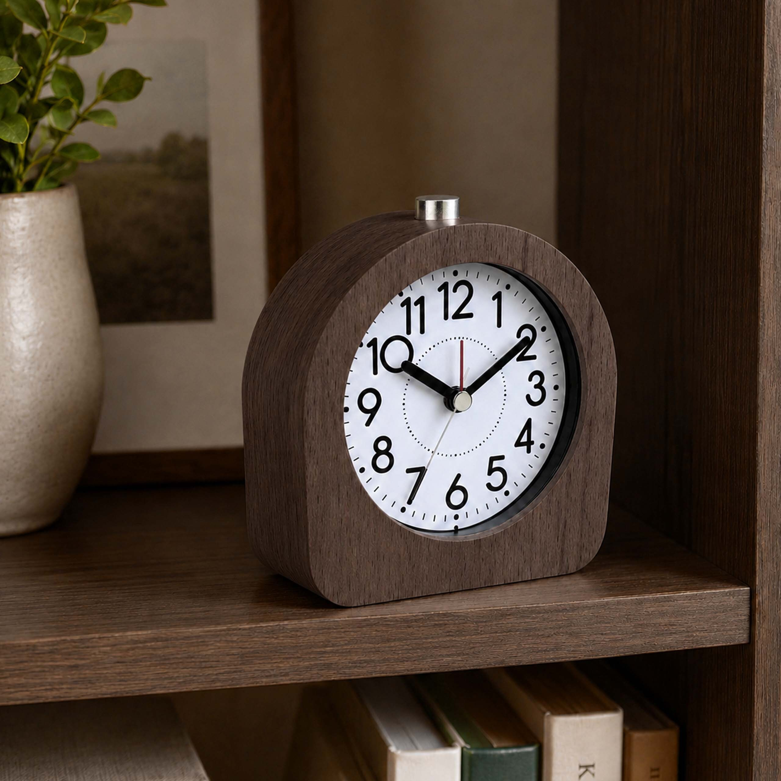 Ein Wecker aus Holz steht auf einem Holzregal neben einer Vase mit grünen Blättern und einem Bild.