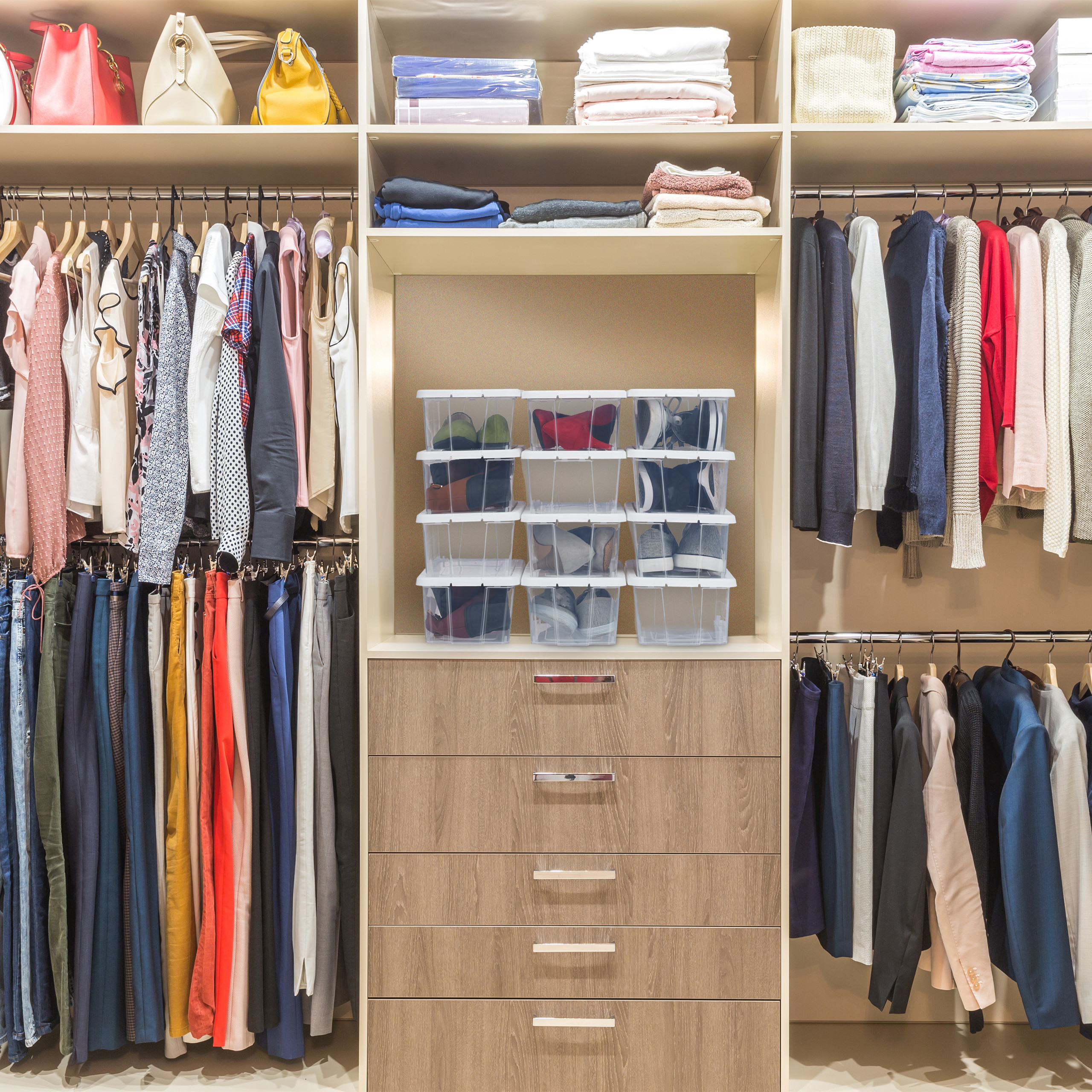 Ein gut organisierter begehbarer Kleiderschrank mit Kleidung auf Bügeln, gefalteten Kleidungsstücken und Schuhen.