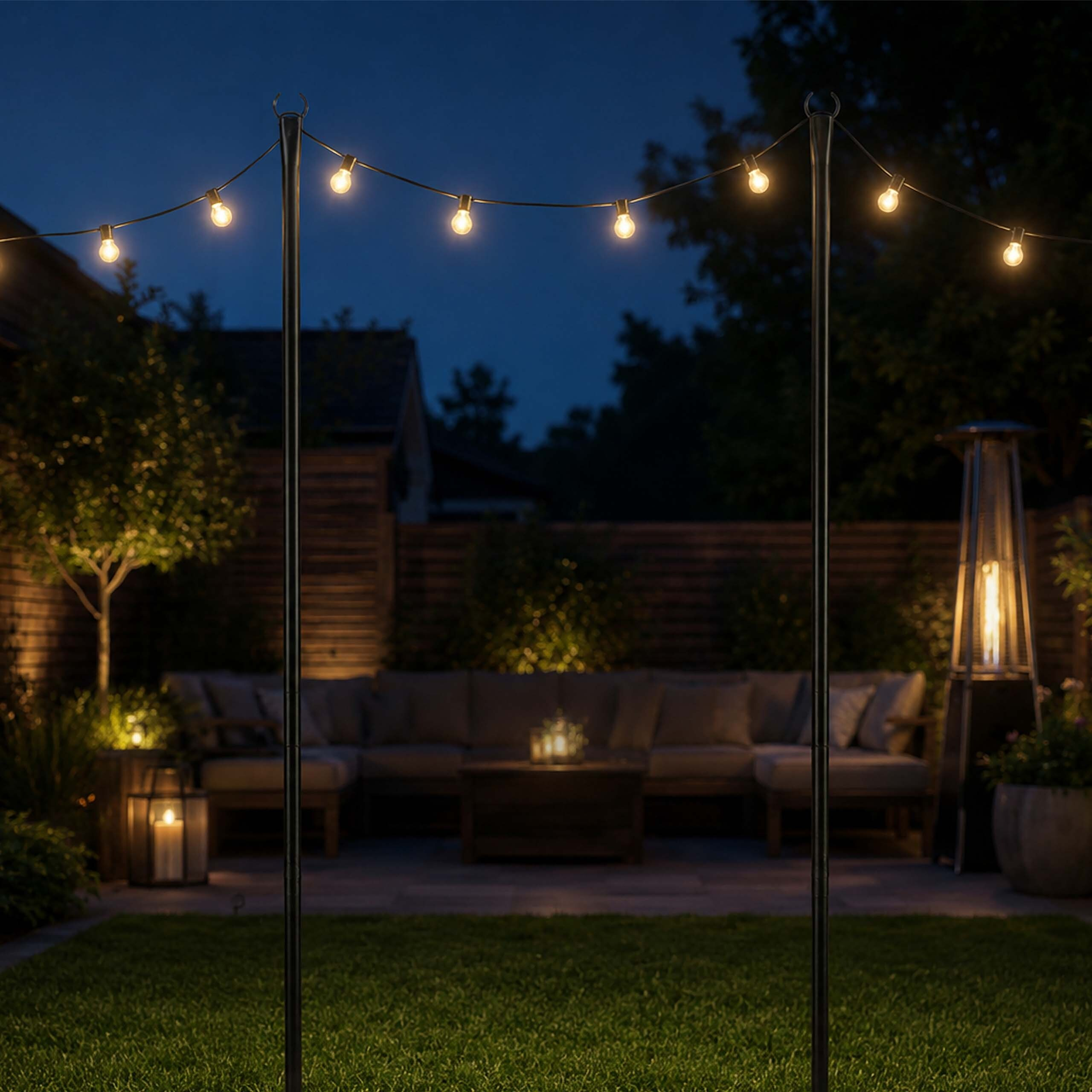 Lichterketten hängen zwischen zwei Metallstangen auf einer schwach beleuchteten Terrasse mit Sitzgelegenheiten.