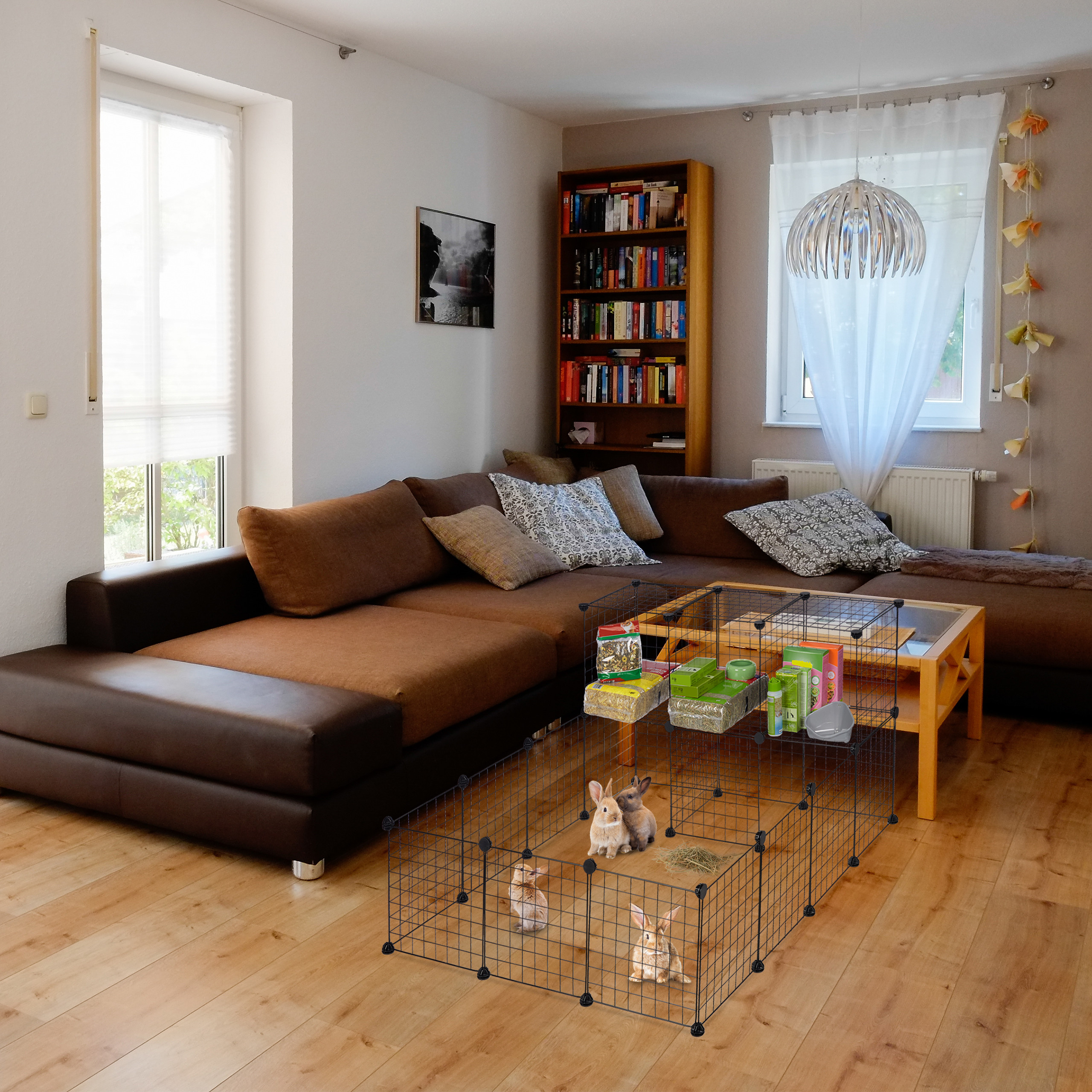 Wohnzimmer mit groBem braunen Sofa und einem Gehege mit mehreren Kaninchen auf dem Holzfussboden.