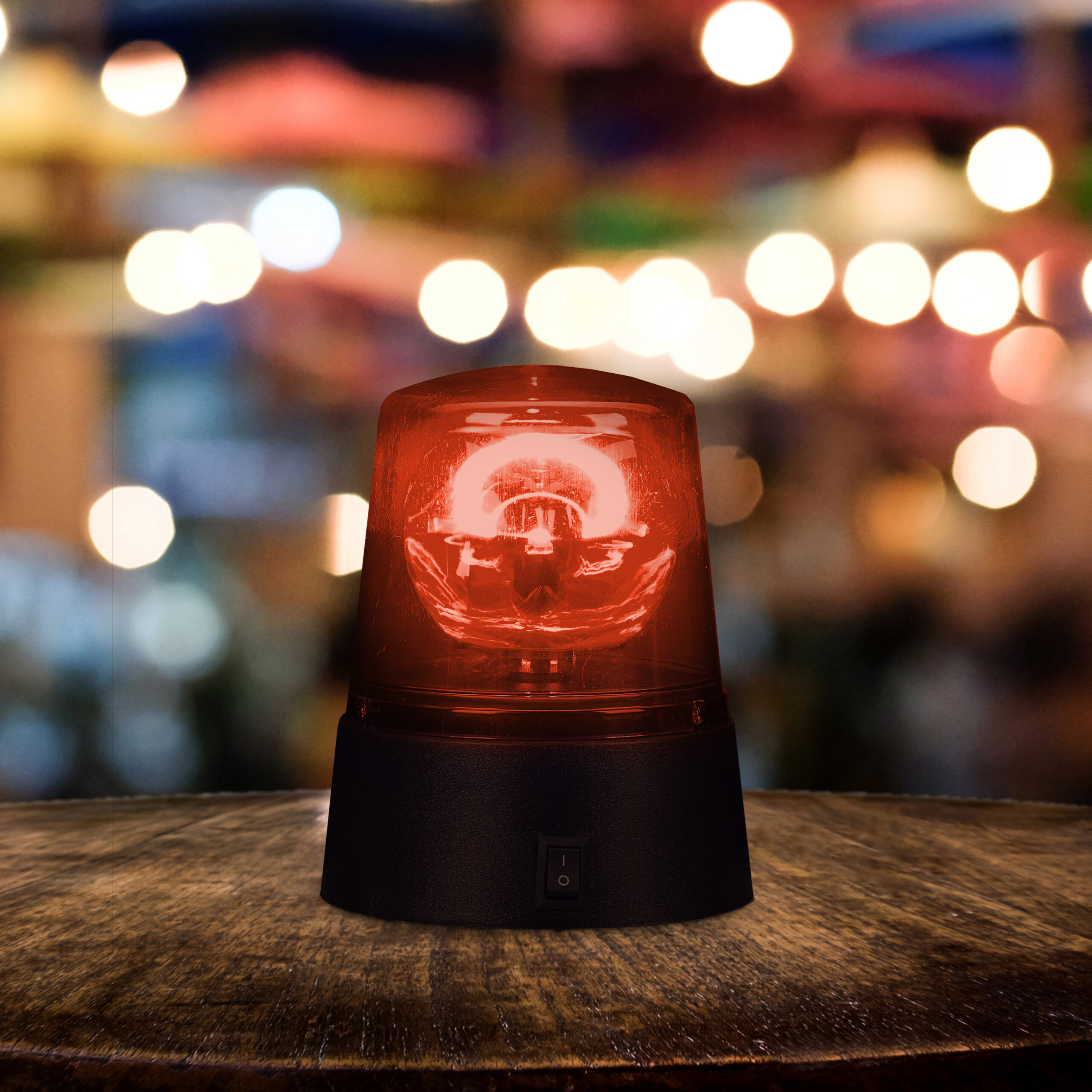 Ein rotes Notlicht auf einem Holztisch vor verschwommenem Hintergrund mit Bokeh-Ländern.