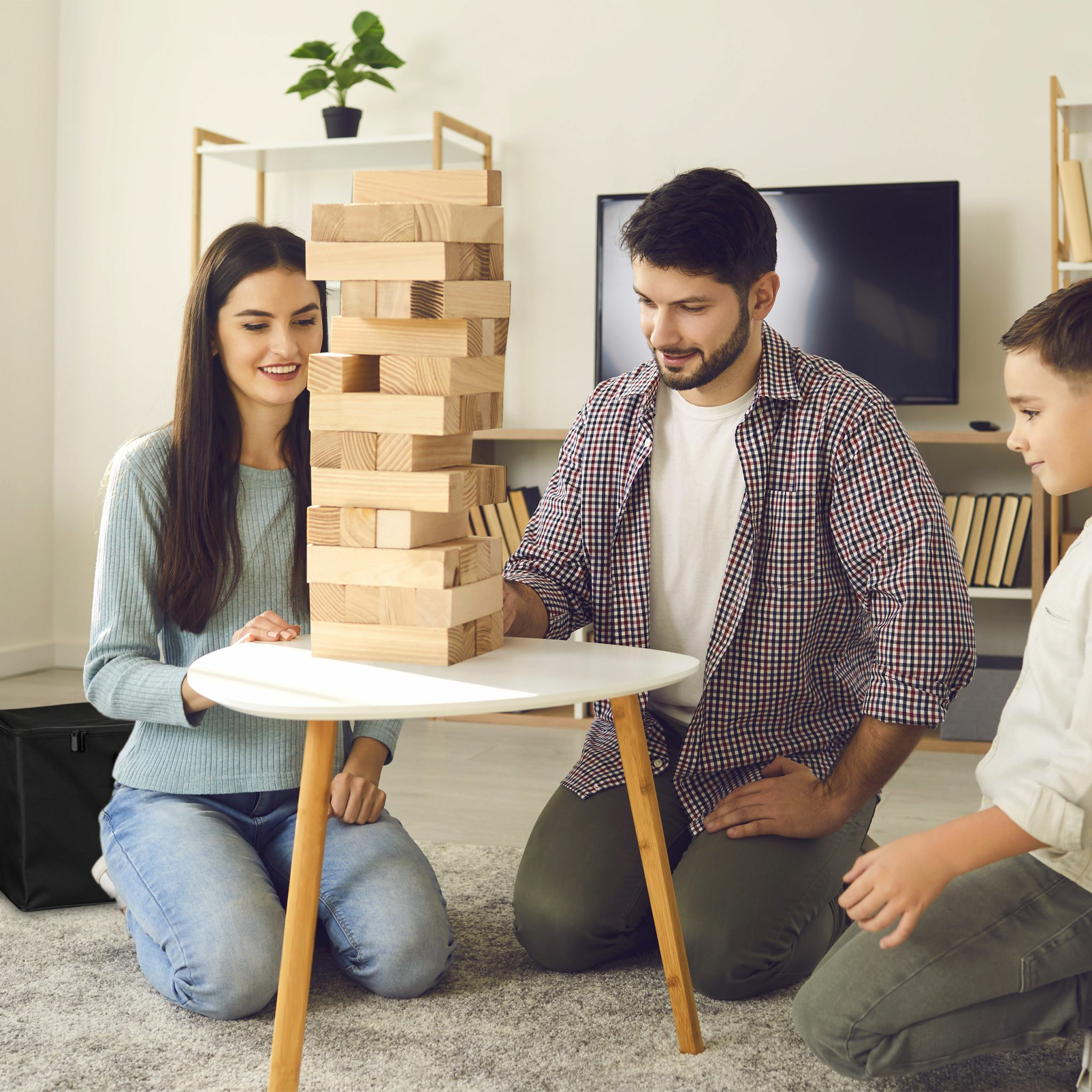 Eine Familie spielt gemeinsam Jenga im Wohnzimmer.