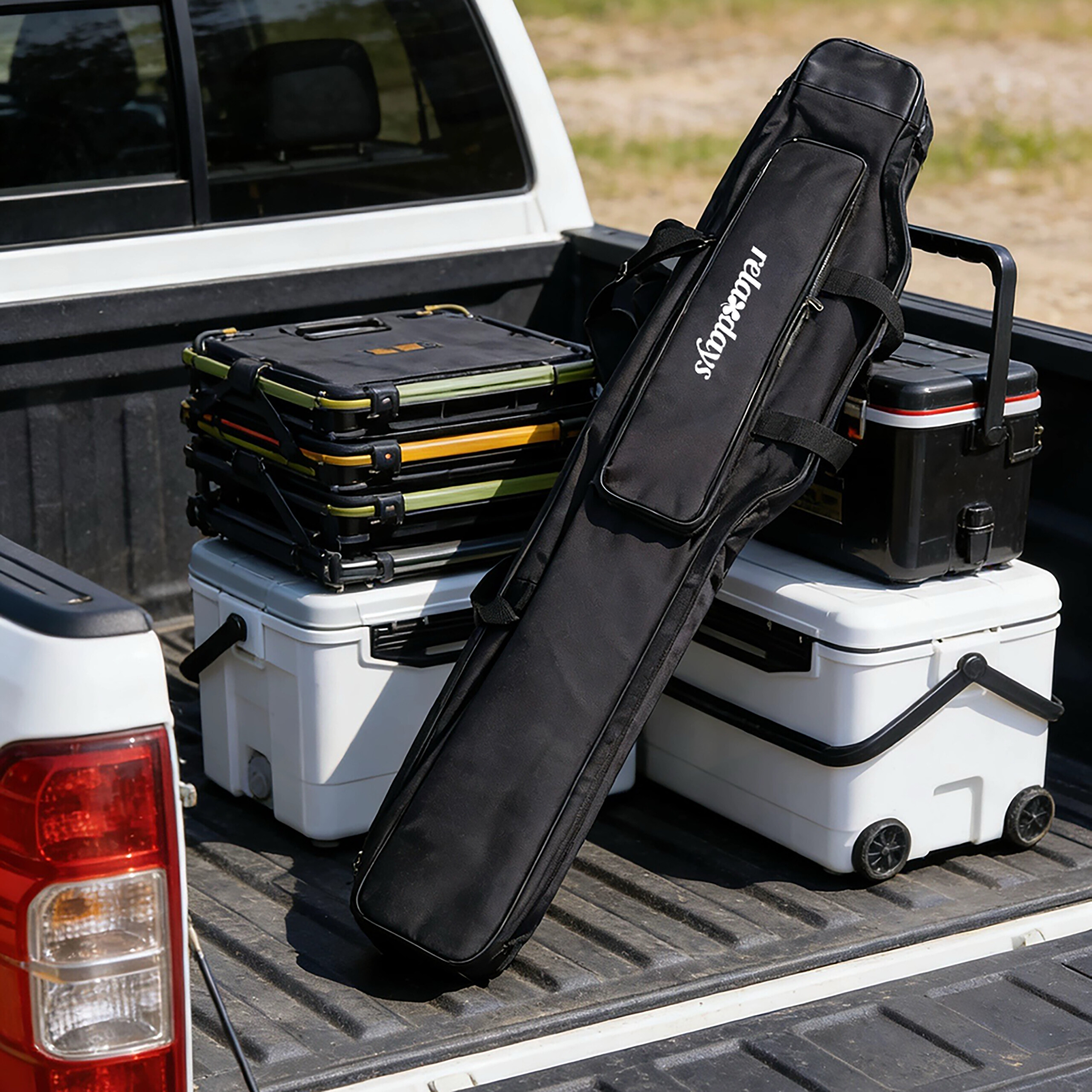 Auf der Ladefläche eines weißen Pickups stehen Kühlboxen, Klapphocker und eine schwarze Angeltasche.