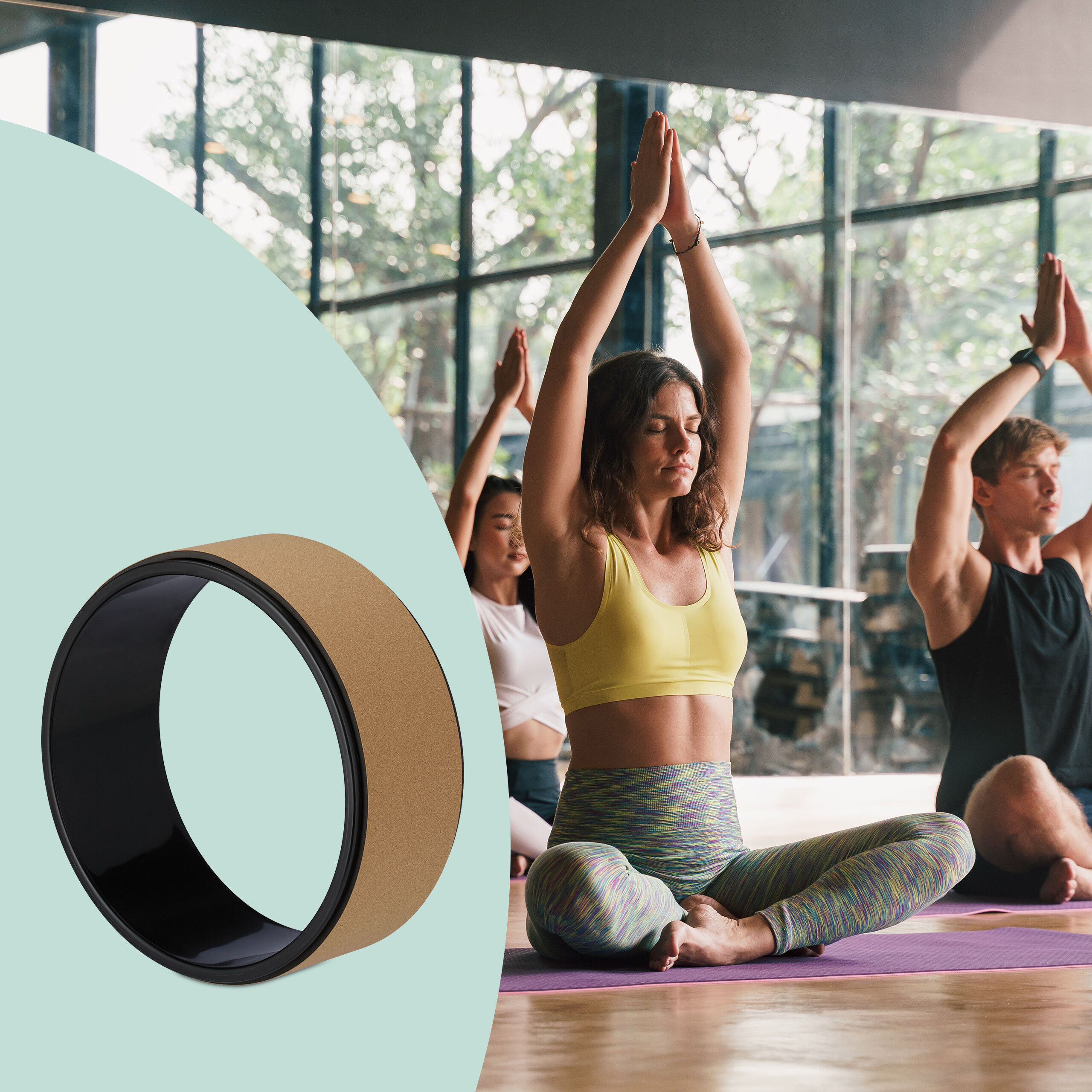 Yoga-Rad mit schwarzem Kern und Korkauflage vor einer Gruppe von Menschen beim Yoga.