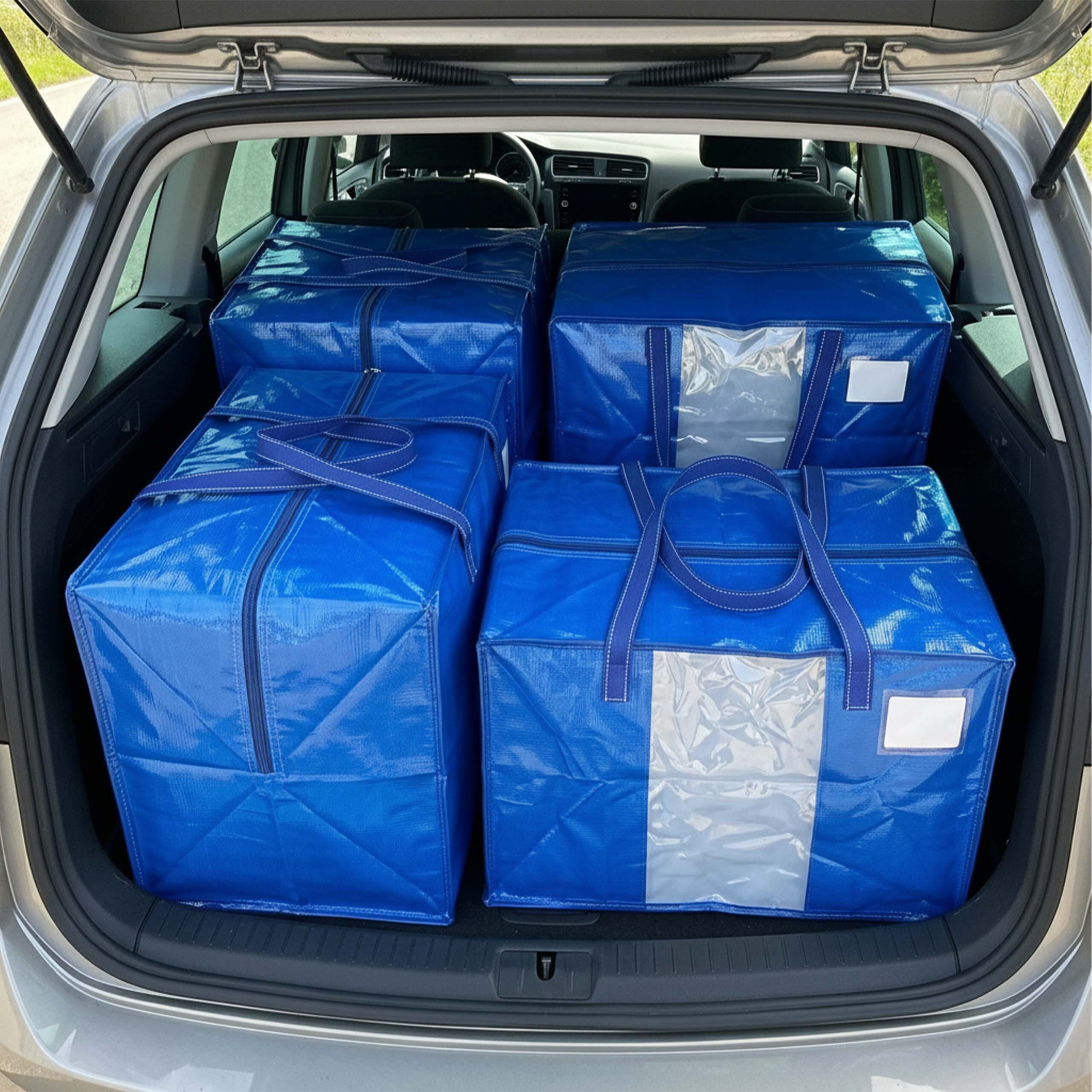 Vier große blaue Einkaufstaschen sind sauber im Kofferraum eines Autos verstaut.