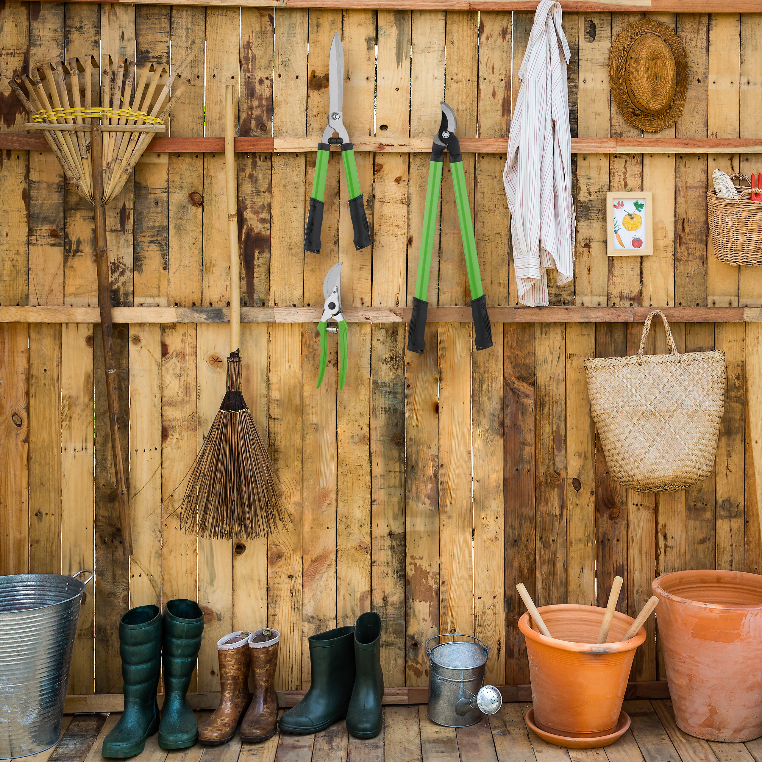 Gartenwerkzeuge und -zubehör wie Rechen, Scheren, Stiefel und Töpfe hängen an einer Holzwand und stehen davor.