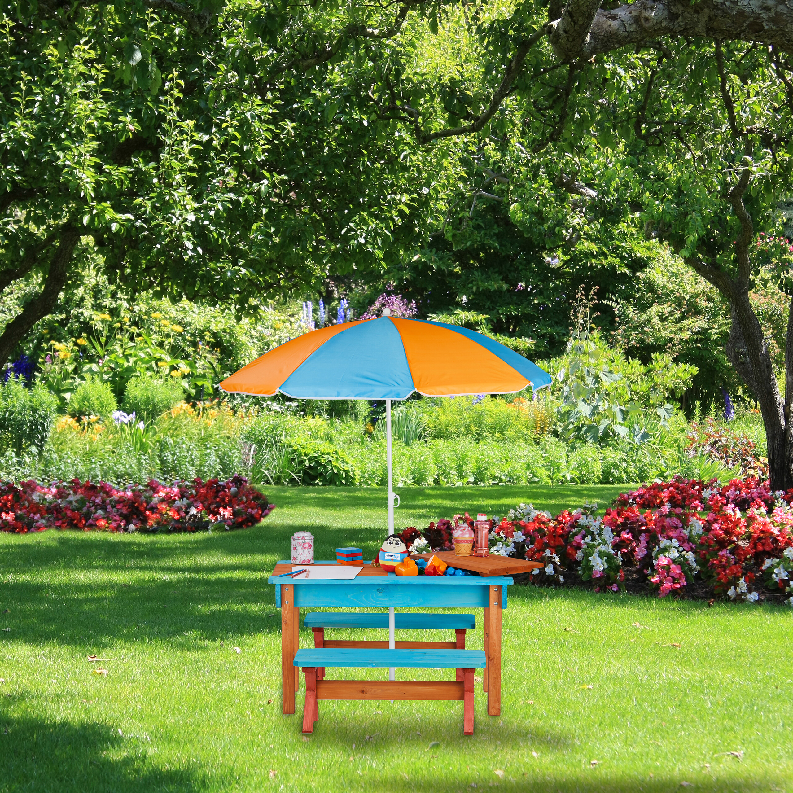 Ein blauer Kindertisch mit Sonnenschirm steht auf einer grünen Wiese im Garten.