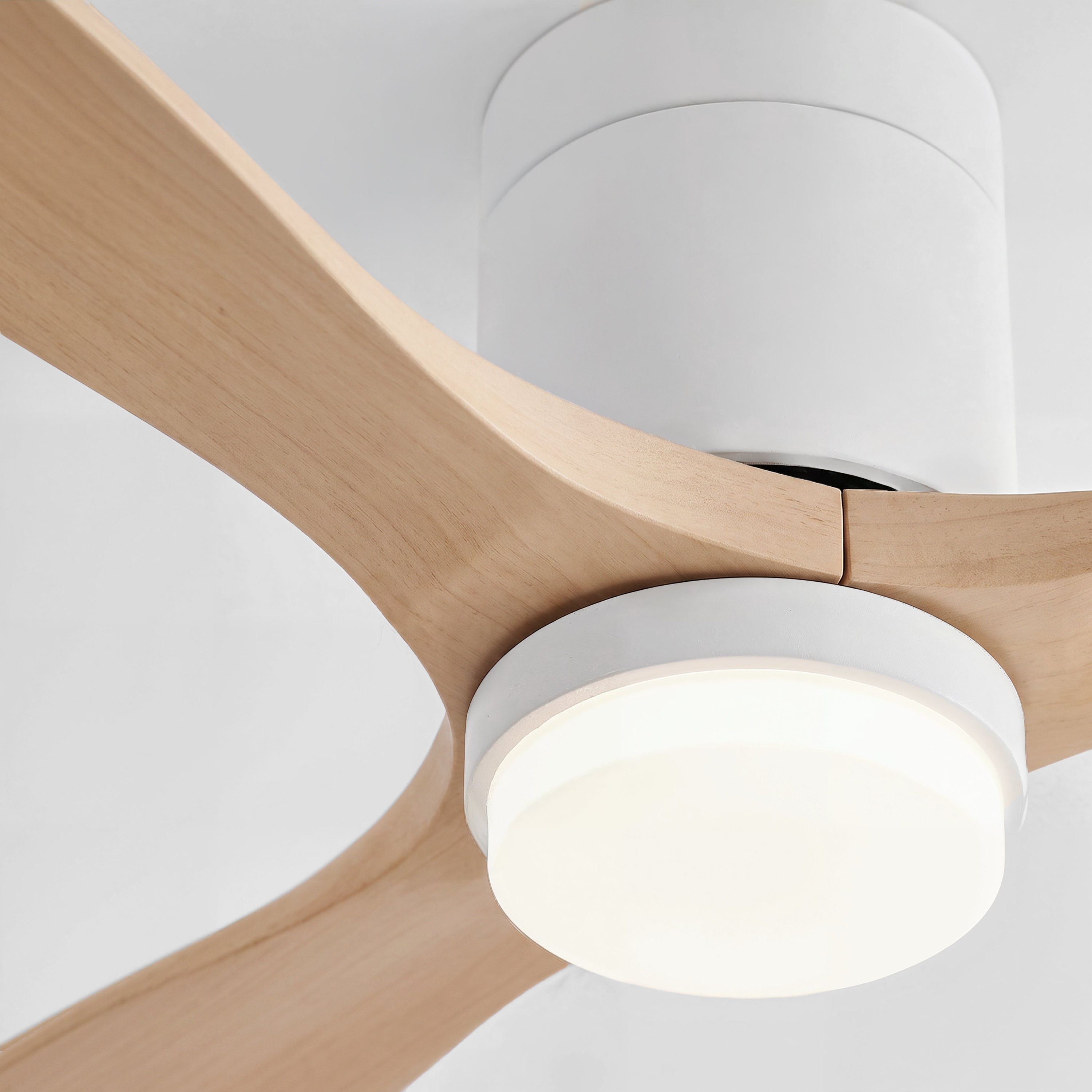Moderno ventilador de techo blanco con aspas de madera clara y centro iluminado contra un techo blanco.
