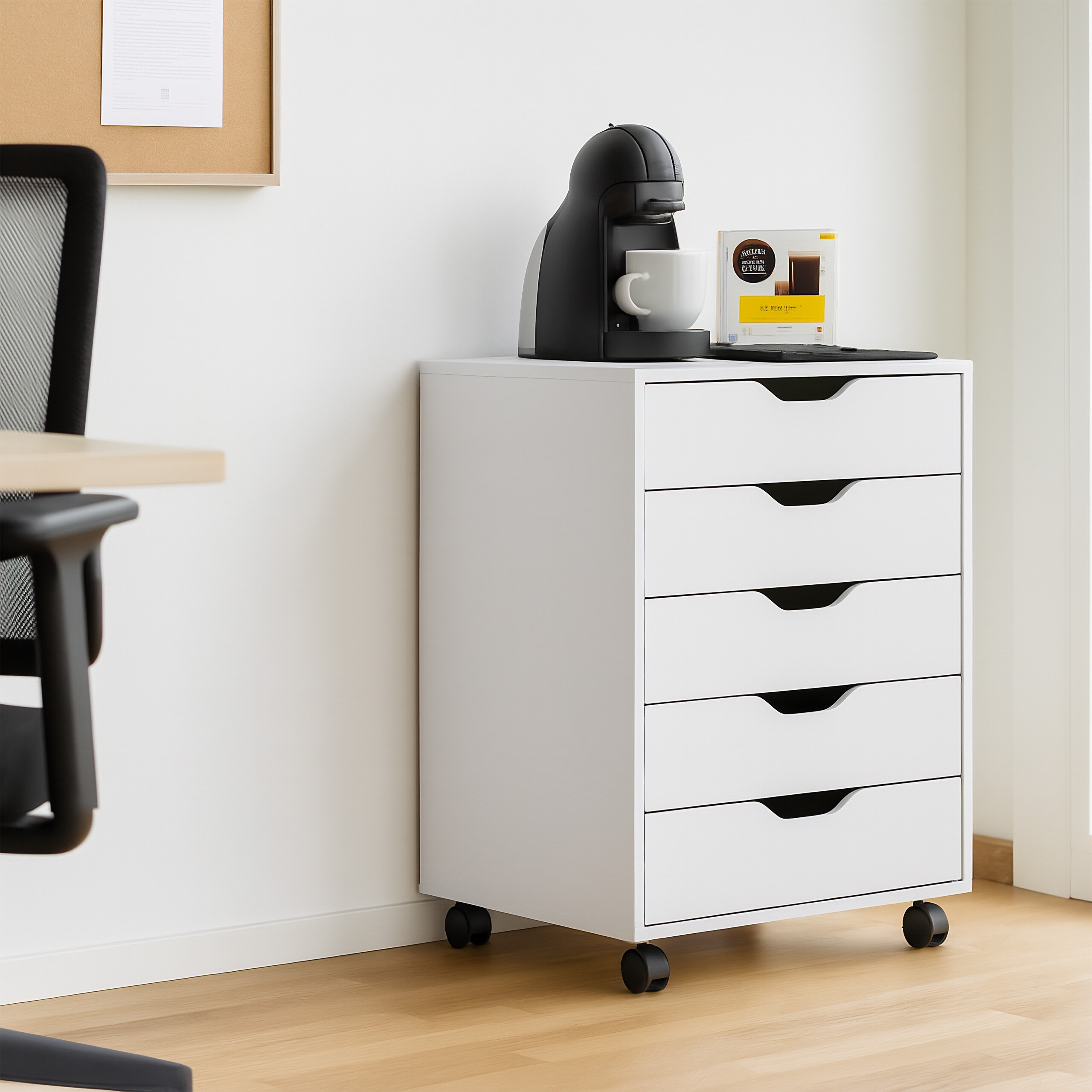 Ein weißer Schubladenschrank auf Rollen mit Kaffeemaschine darauf, neben einem Bürostuhl.