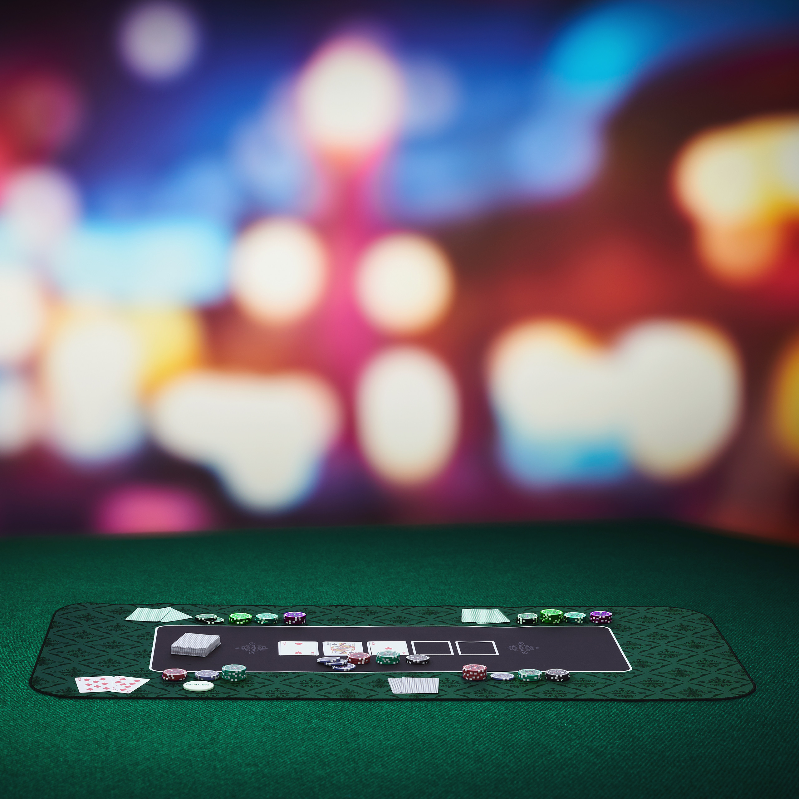 Ein Pokertisch mit Karten, Chips und einem Deck vor einem verschwommenen Bokeh-Hintergrund.