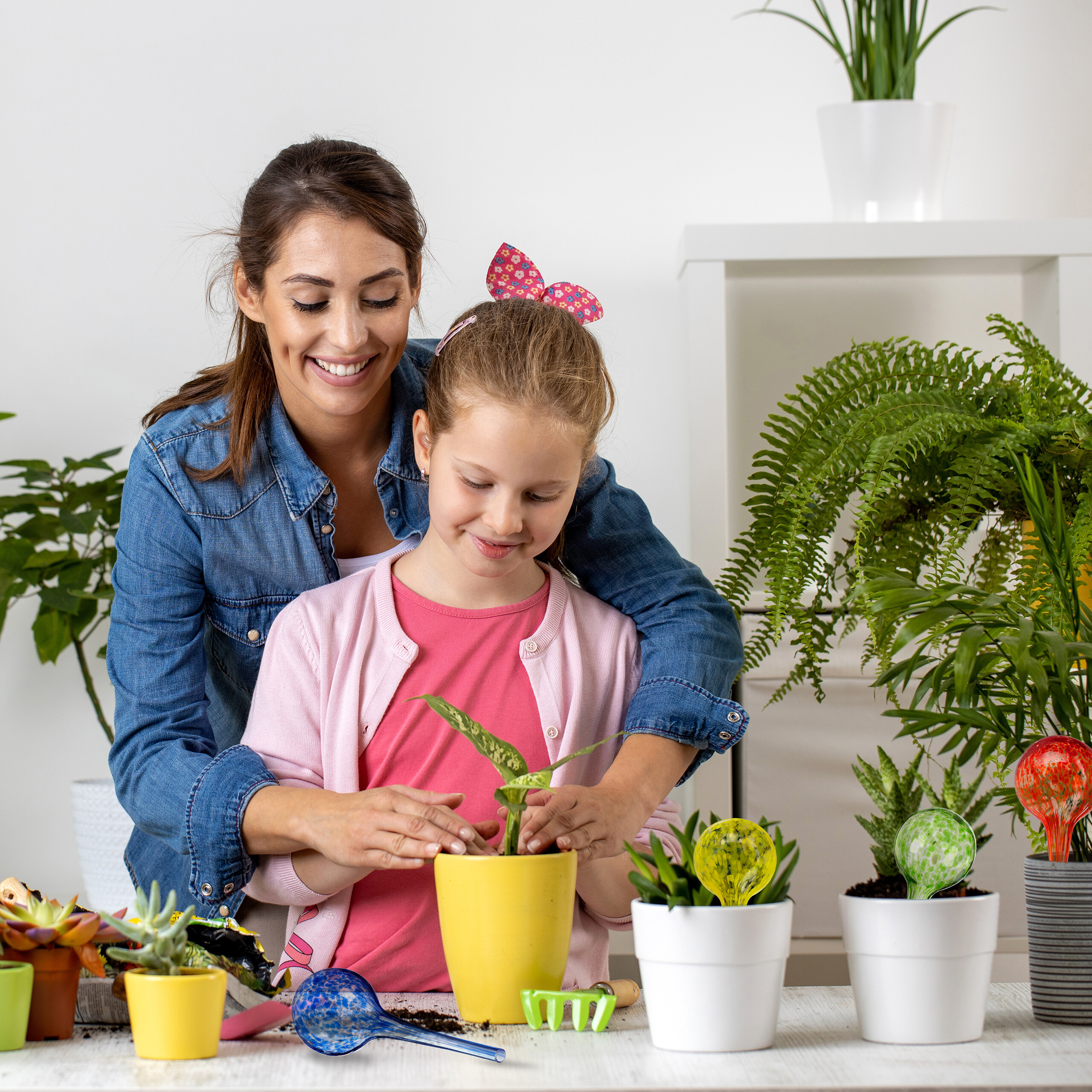 Eine Frau und ein Mädchen pflanzen zusammen Blumen in Töpfe.