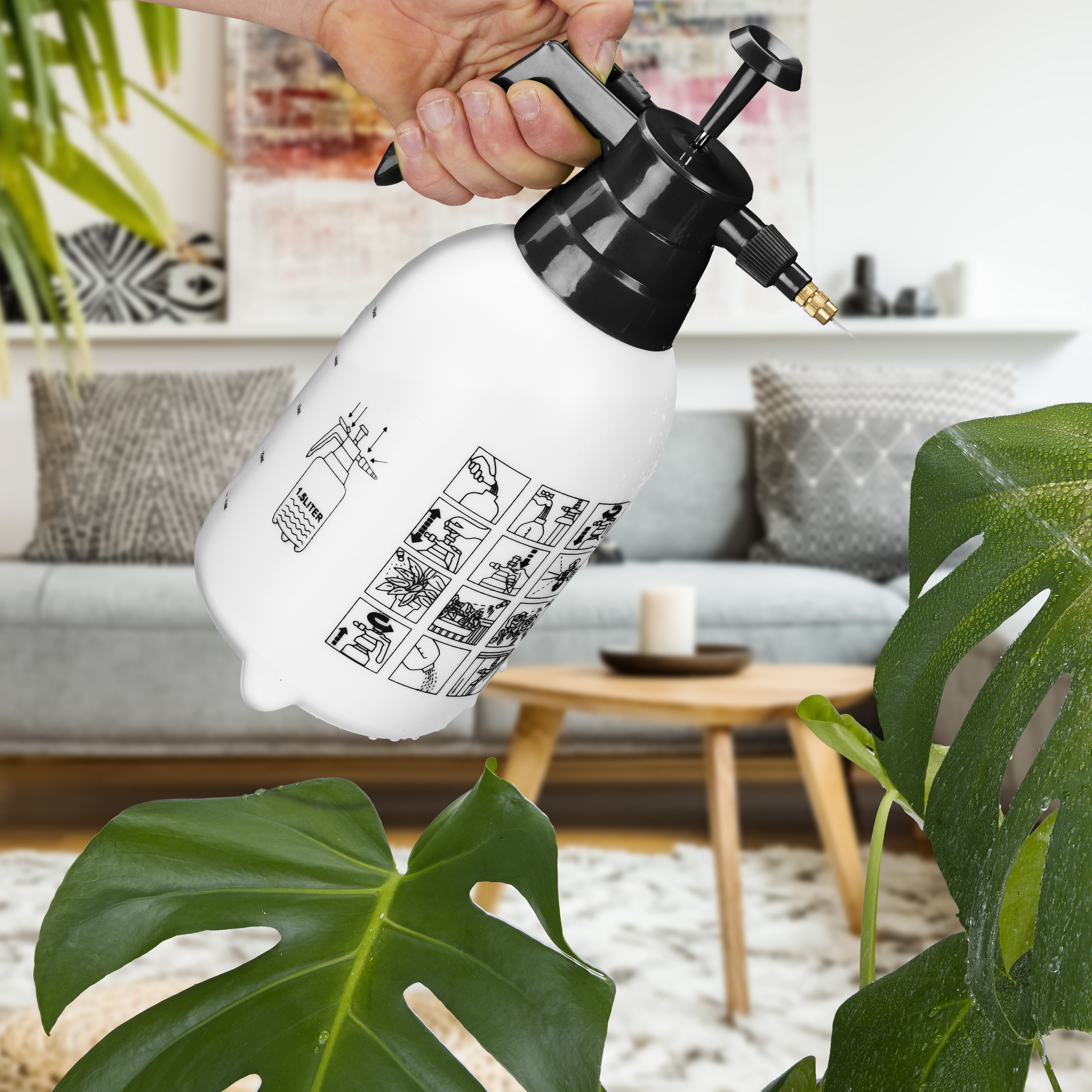 Hand hält weiße Pumpsprühflasche, um Monstera-Pflanze in einem Wohnzimmer zu besprühen.