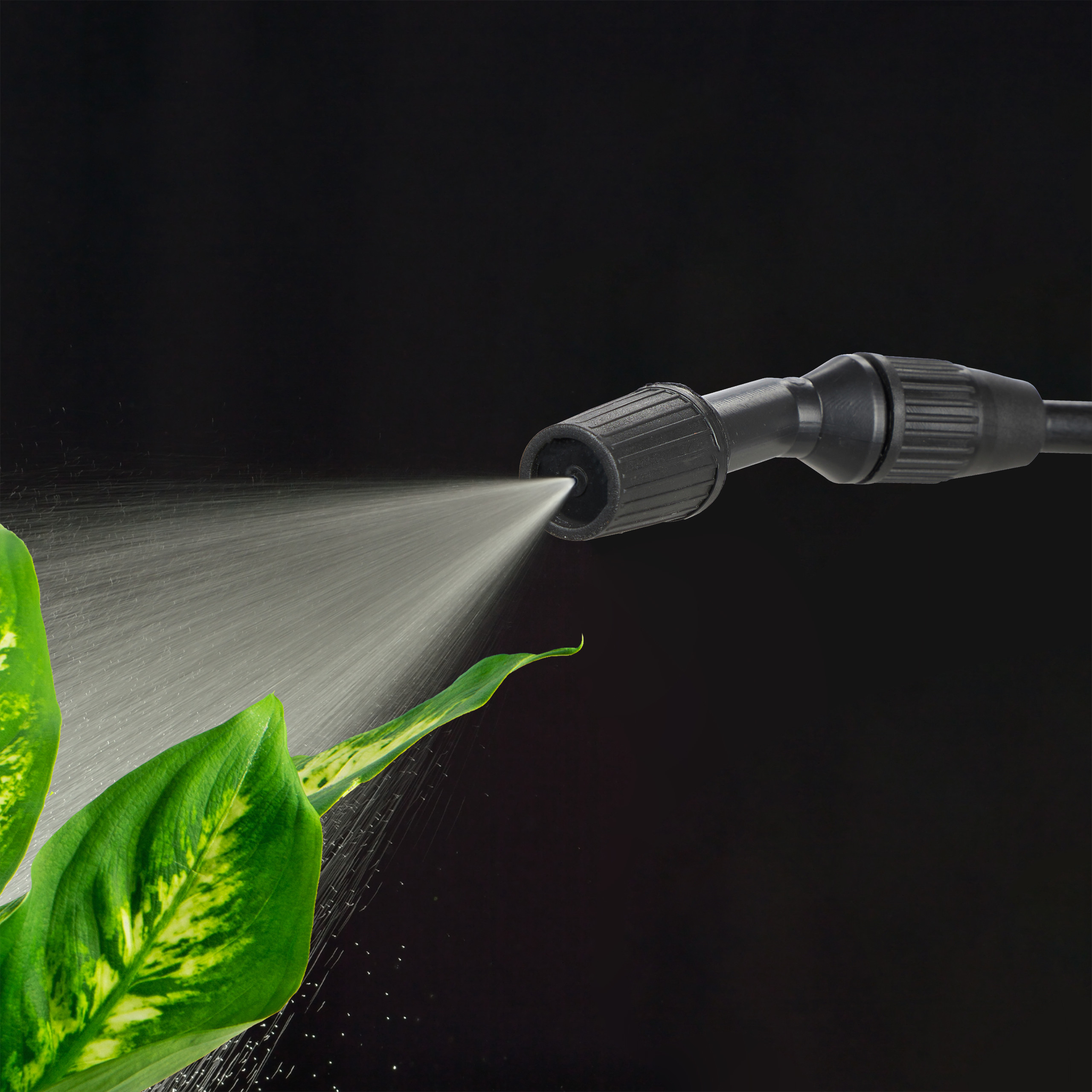 Ein schwarzer Sprühkopf sprüht Wasser auf grüne Blätter vor schwarzem Hintergrund.