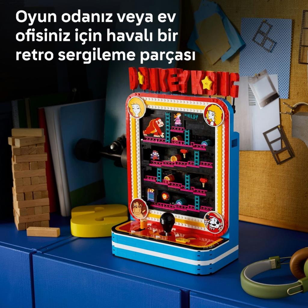 Mavi bir masa üzerinde oyuncaklar ve notlarla çevrili bir Lego Donkey Kong atari makinesi.