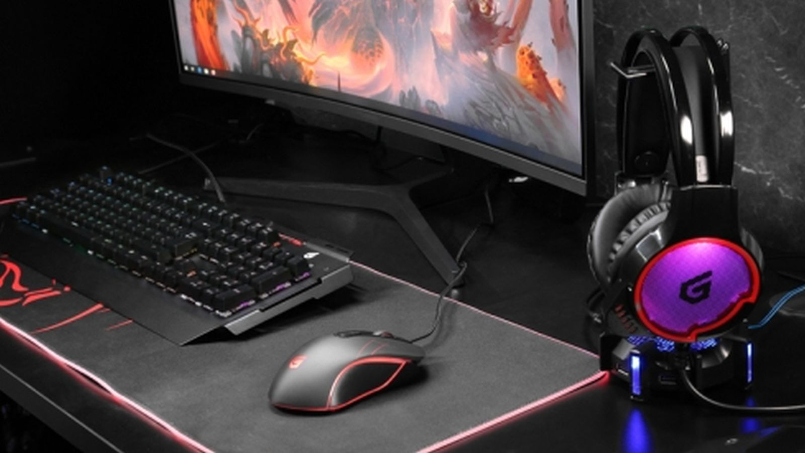 Postazione da gioco con tastiera, mouse, monitor e cuffie RGB su supporto.