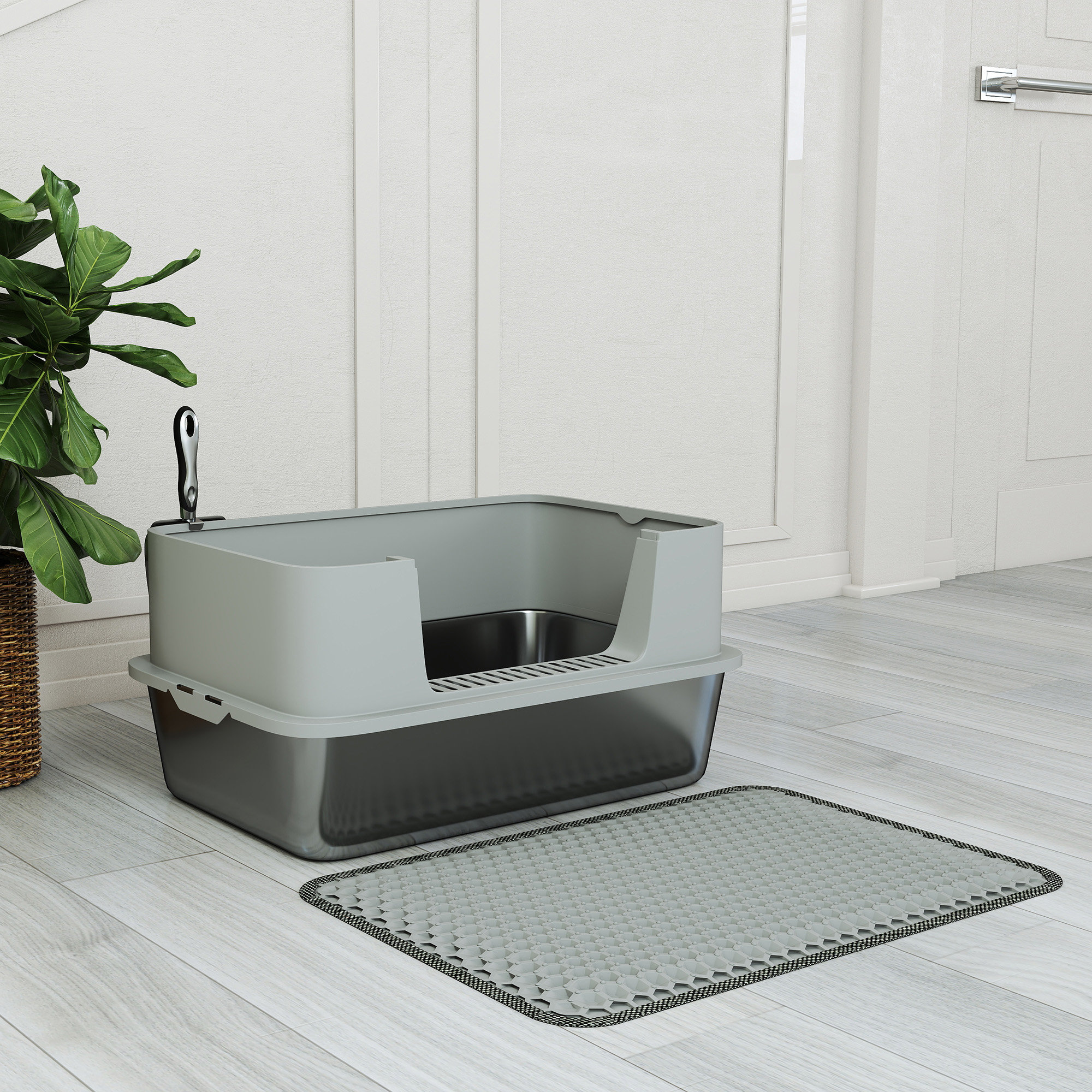 Un arenero gris para gatos con pala y estera en suelo de madera clara en una habitación blanca con planta.