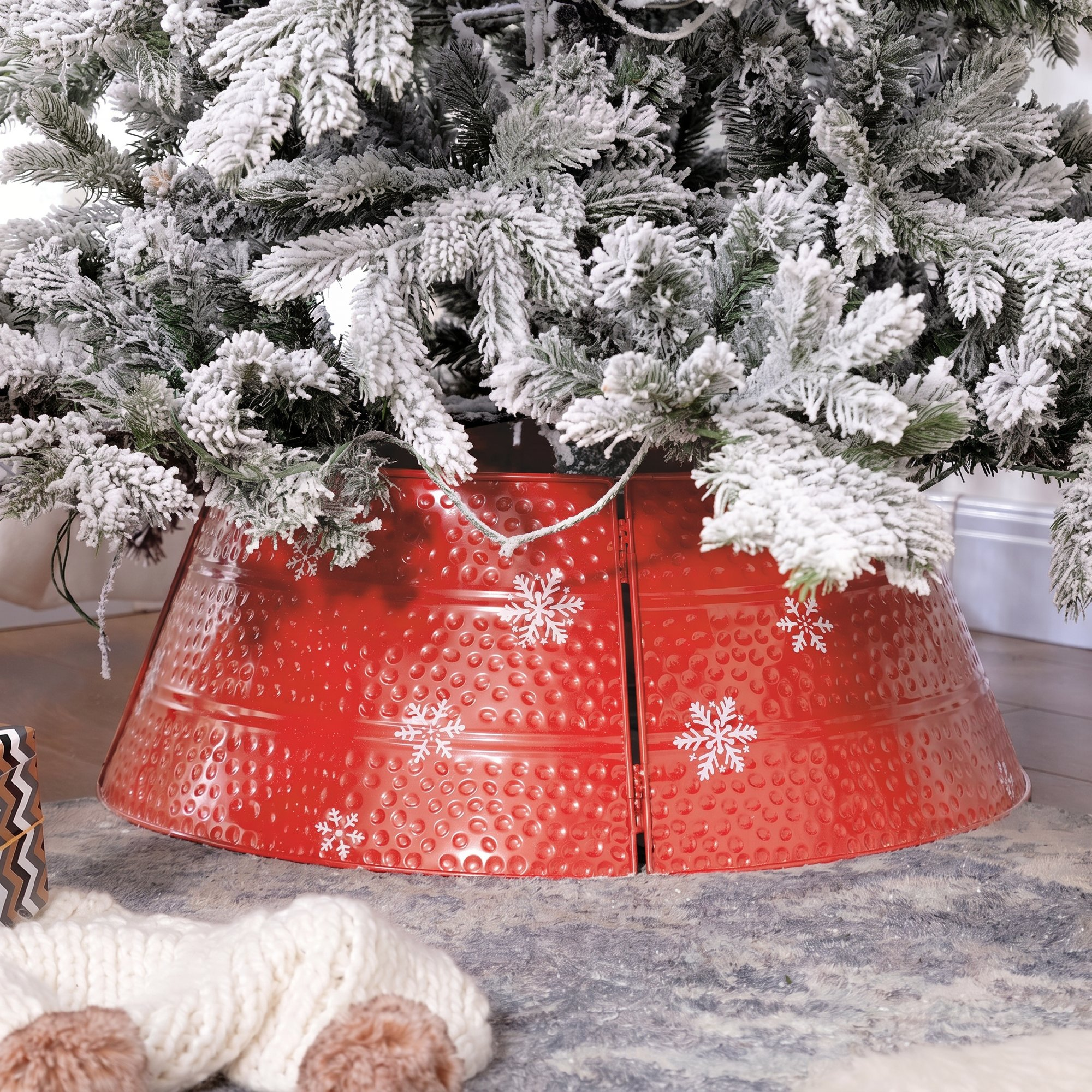 Collar rojo texturizado para árbol de Navidad con copos blancos bajo un árbol nevado.