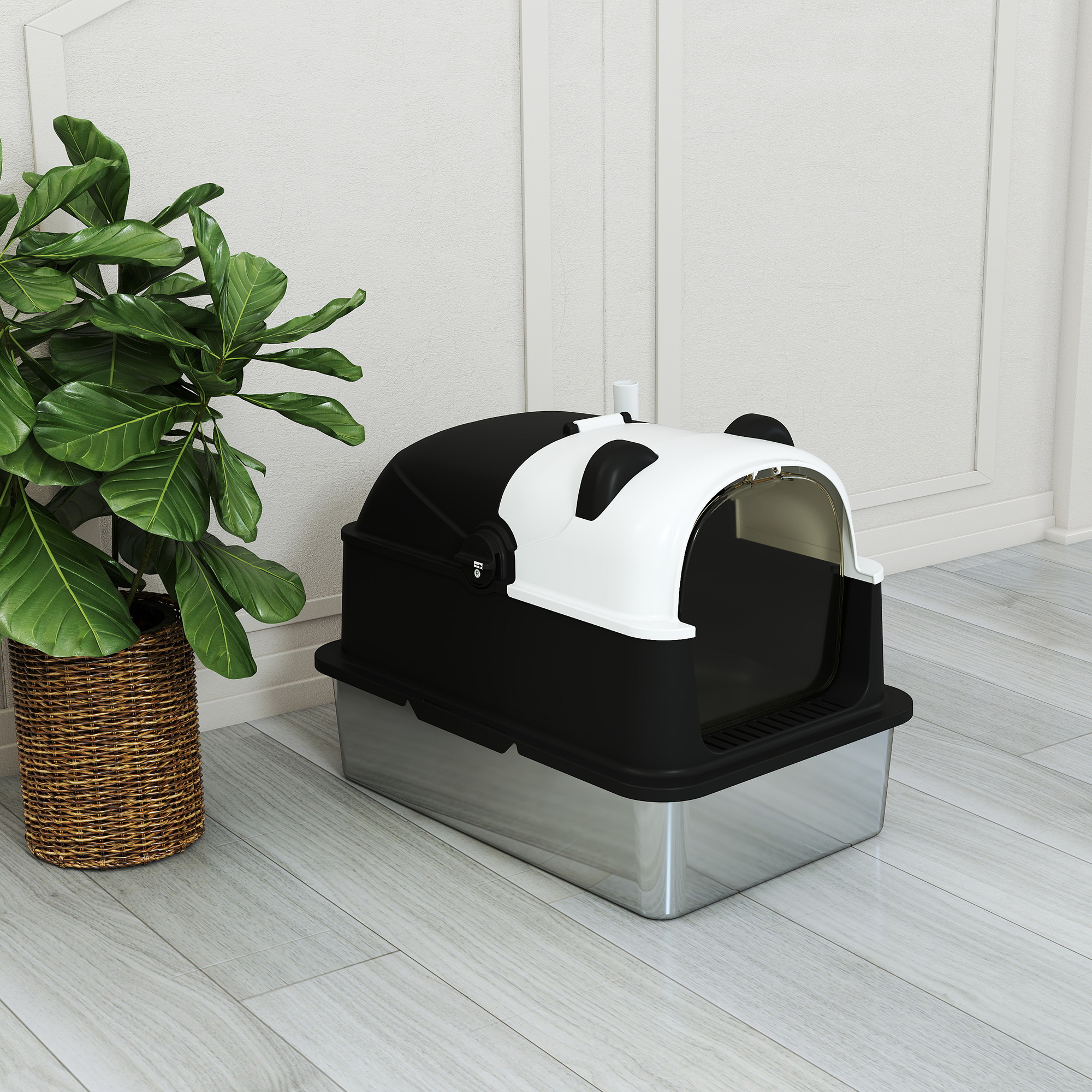 Un arenero para gatos en blanco y negro con diseño de panda sobre suelo de madera junto a una planta verde.