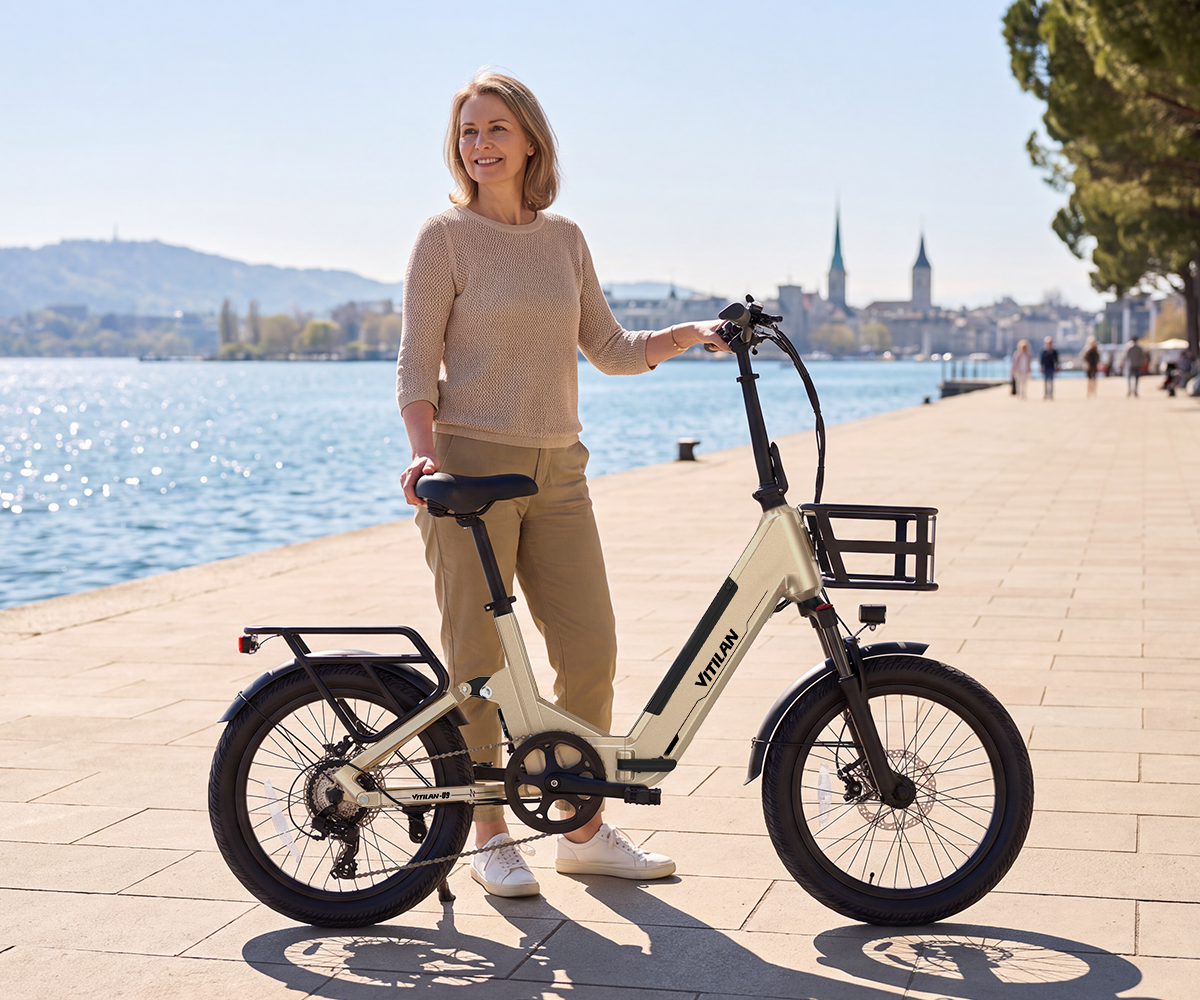 Una mujer en un paseo marítimo sostiene una bicicleta eléctrica color crema con cesta delantera.