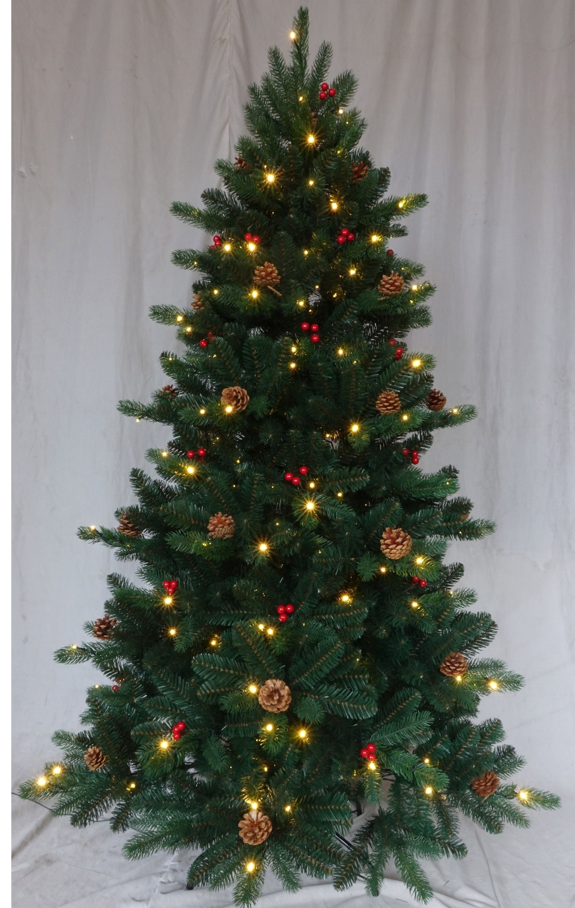 Un árbol de Navidad decorado con luces cálidas, piñas y bayas rojas sobre un fondo claro.