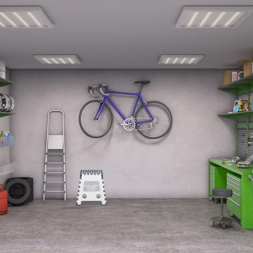 Eine gut organisierte Werkstatt mit einem blauen Fahrrad an der Wand, einer Leiter und grünem Werkbank.