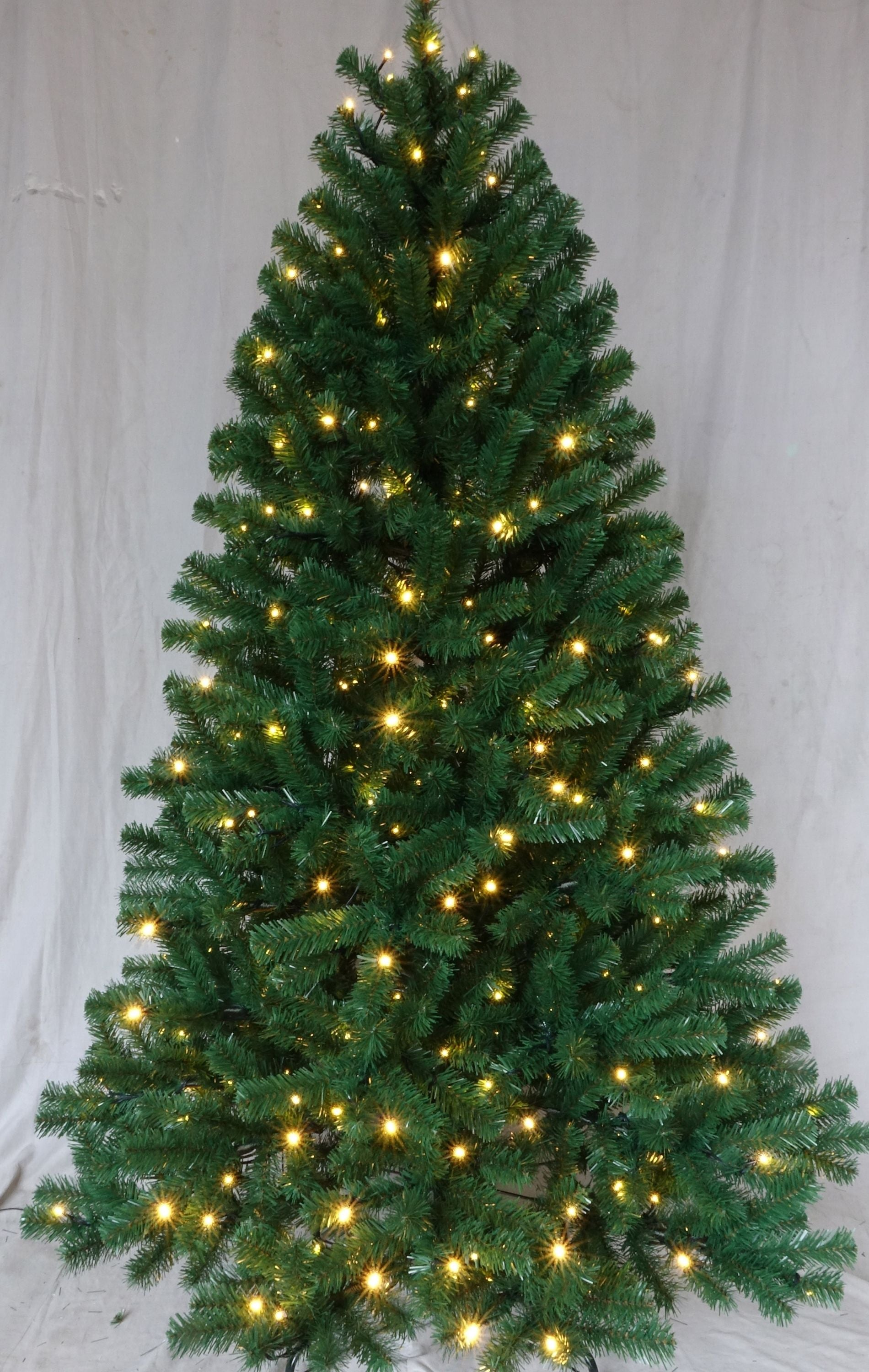 Un árbol de Navidad verde artificial decorado con luces blancas cálidas sobre fondo blanco.