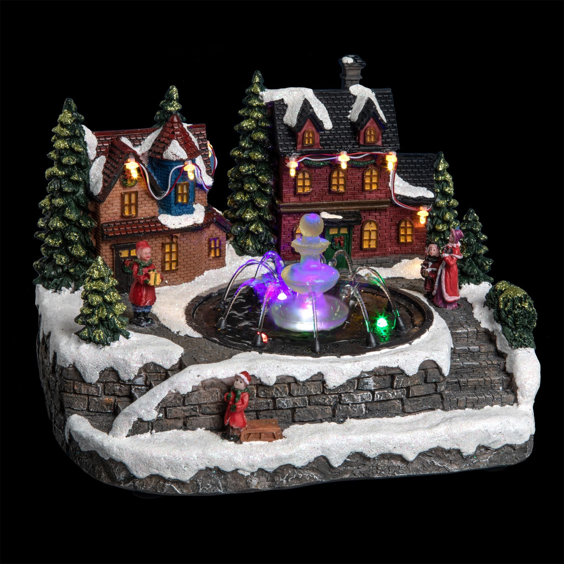 Pueblo navideño iluminado con luces de colores, nieve, casas nevadas, pinos y una fuente de agua central brillante.