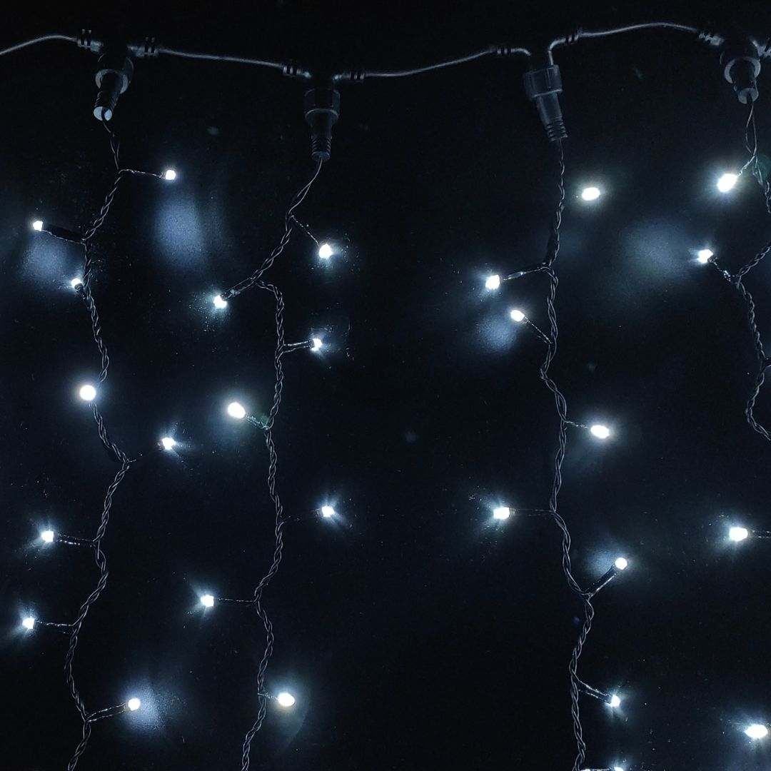 Luces de cadena blancas brillantes cuelgan sobre un fondo oscuro.