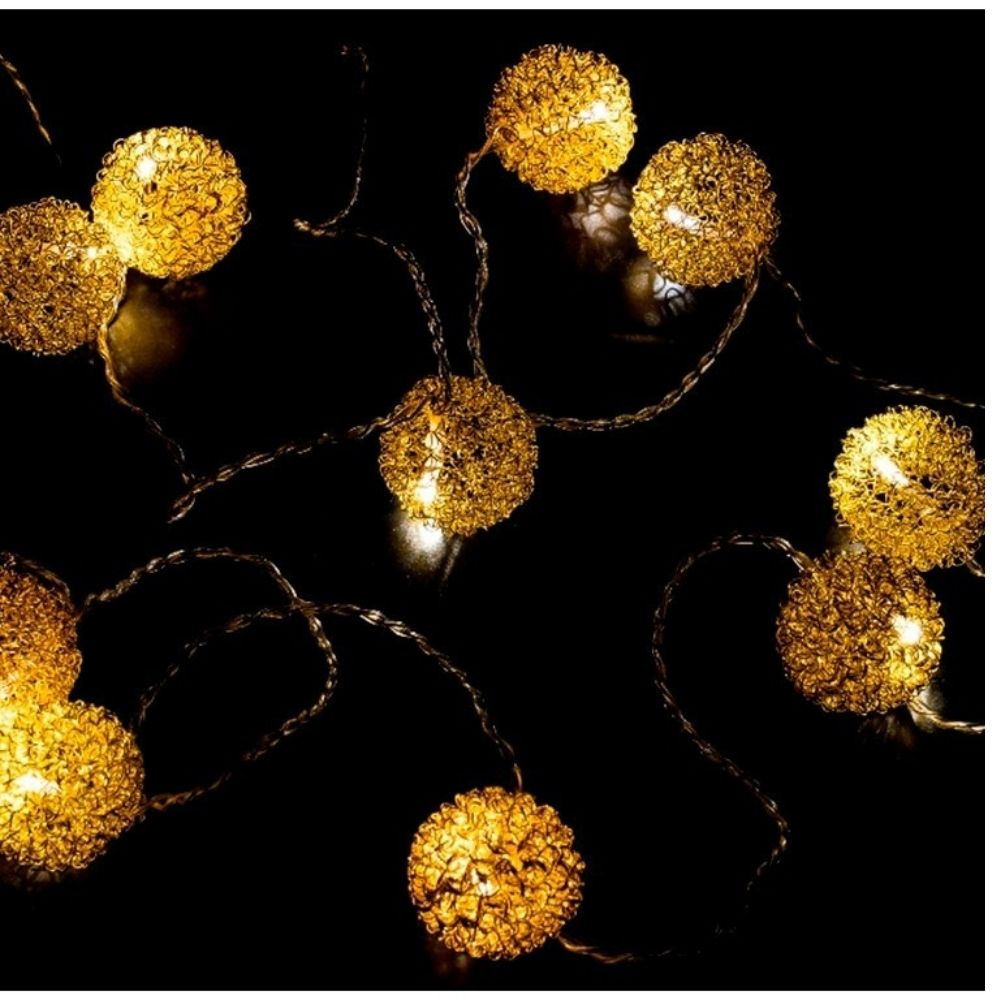 Luces de cadena esféricas doradas brillando sobre un fondo negro oscuro.