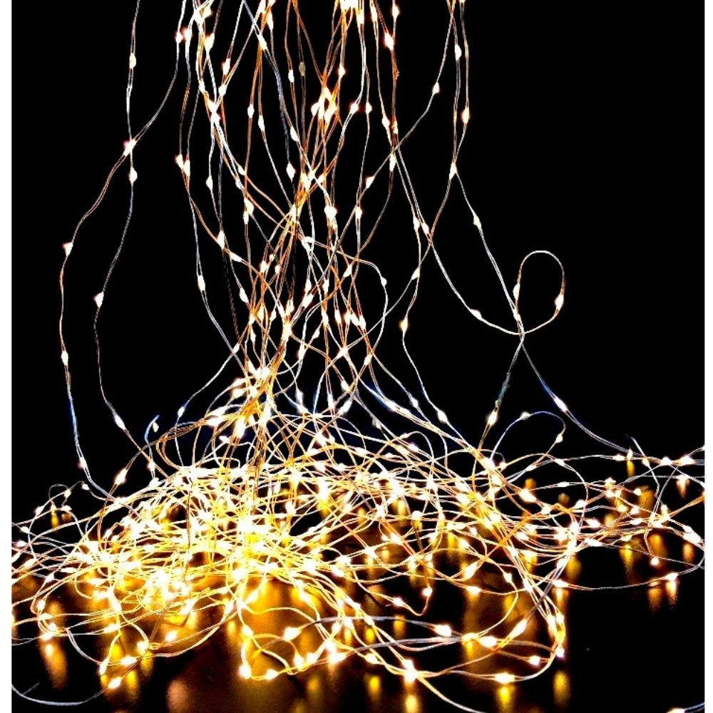 Luces de hadas brillantes cuelgan y forman un montón luminoso en el suelo sobre un fondo negro.