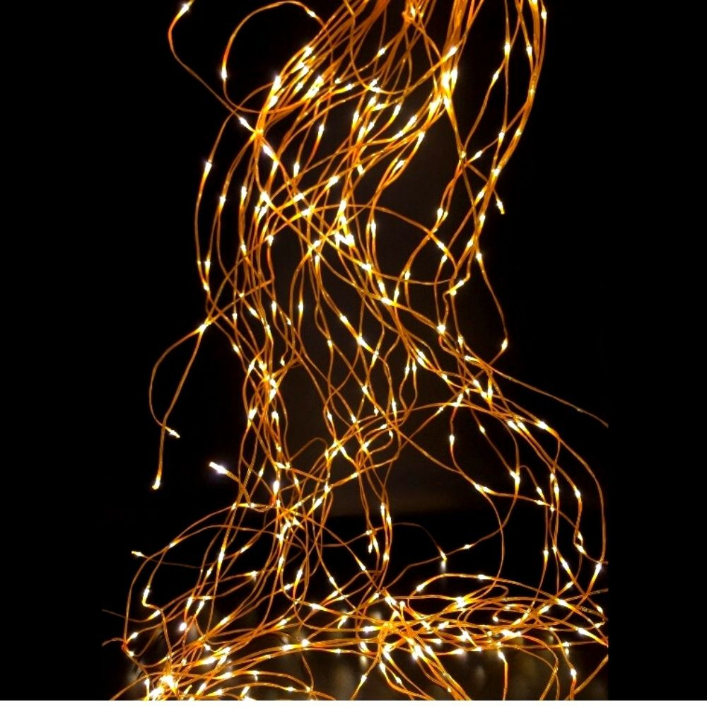 Luces de hadas cálidas y brillantes caen sobre un fondo negro, creando un patrón enredado y luminoso.