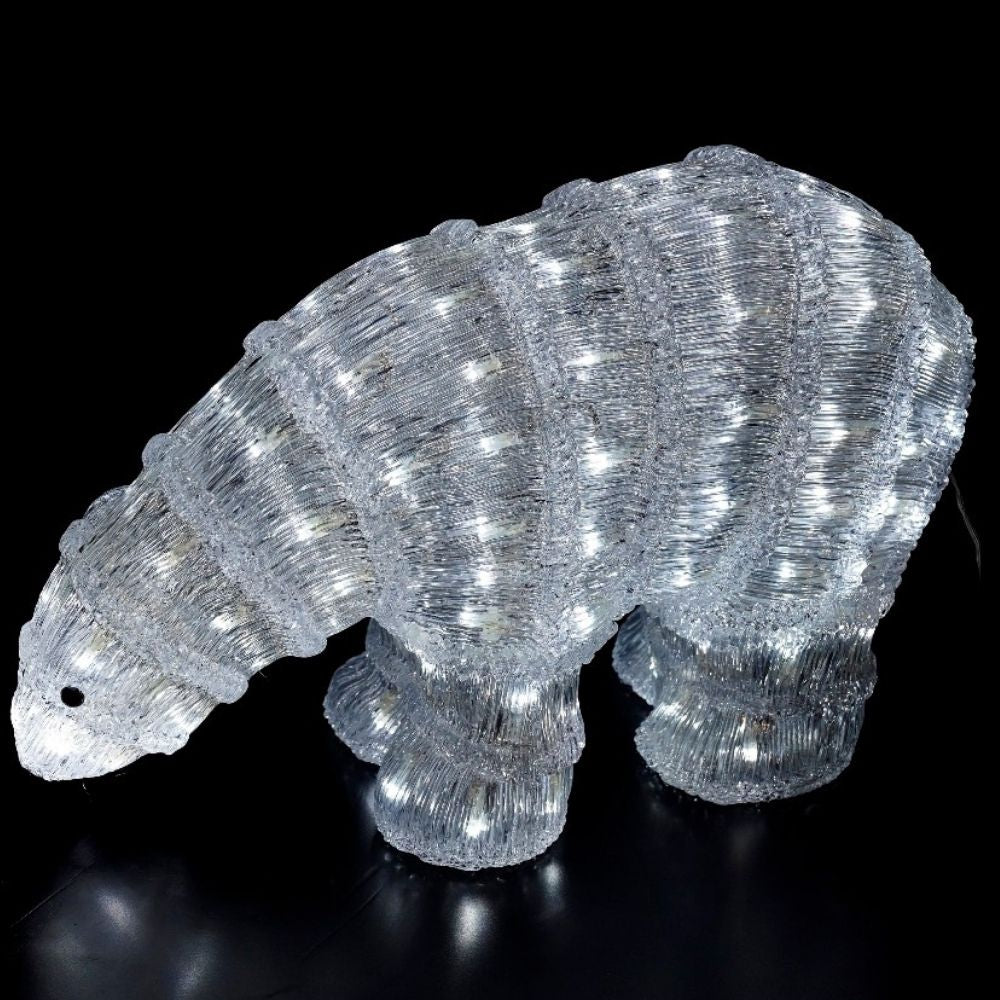 Una escultura de oso polar iluminada hecha de material de oropel transparente sobre un fondo oscuro.